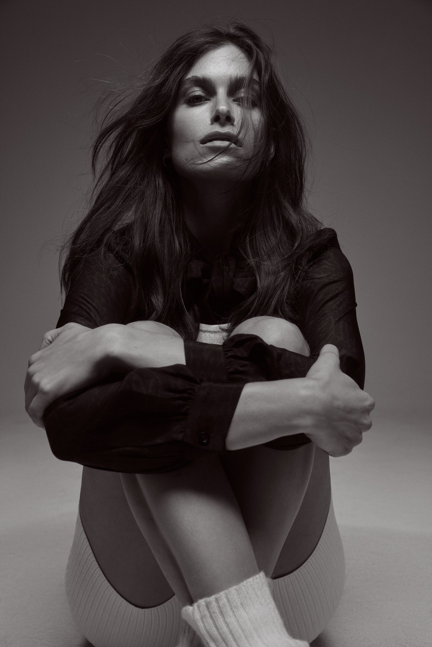 a black and white photo of a woman sitting on the floor