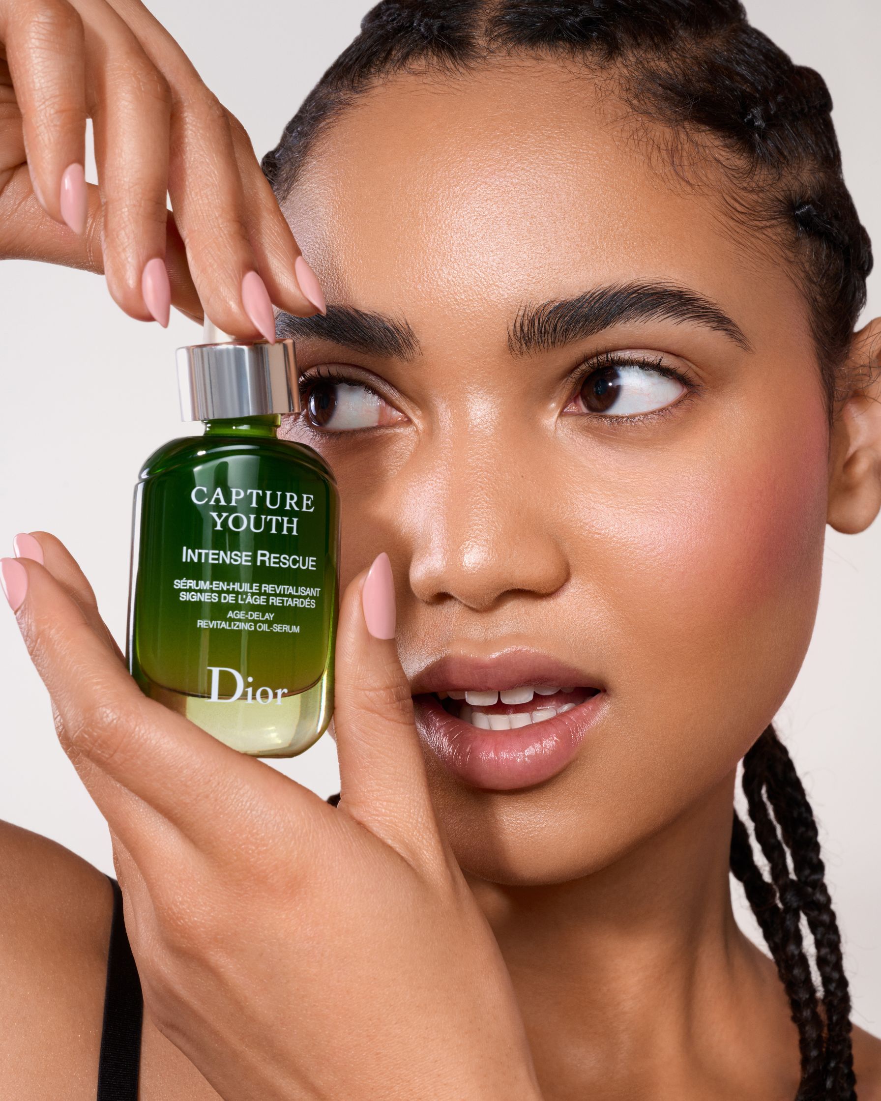 a woman is holding up a bottle of green tea oil