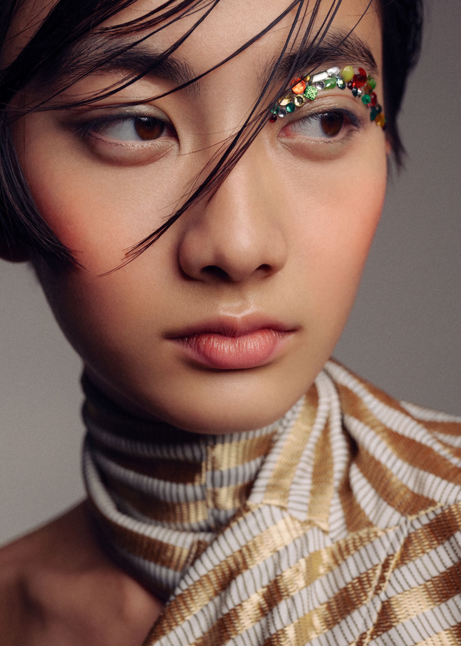 a young woman wearing a striped dress and gold eye makeup
