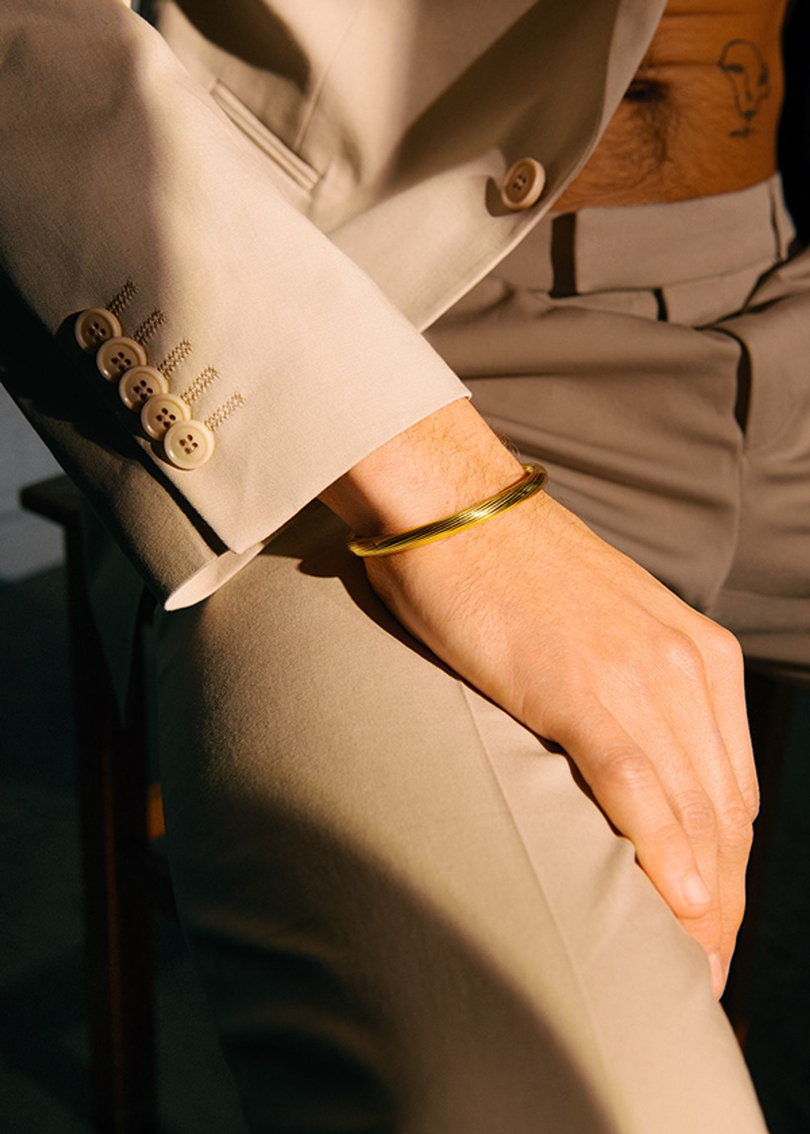 a man sitting on a chair wearing a gold cuff
