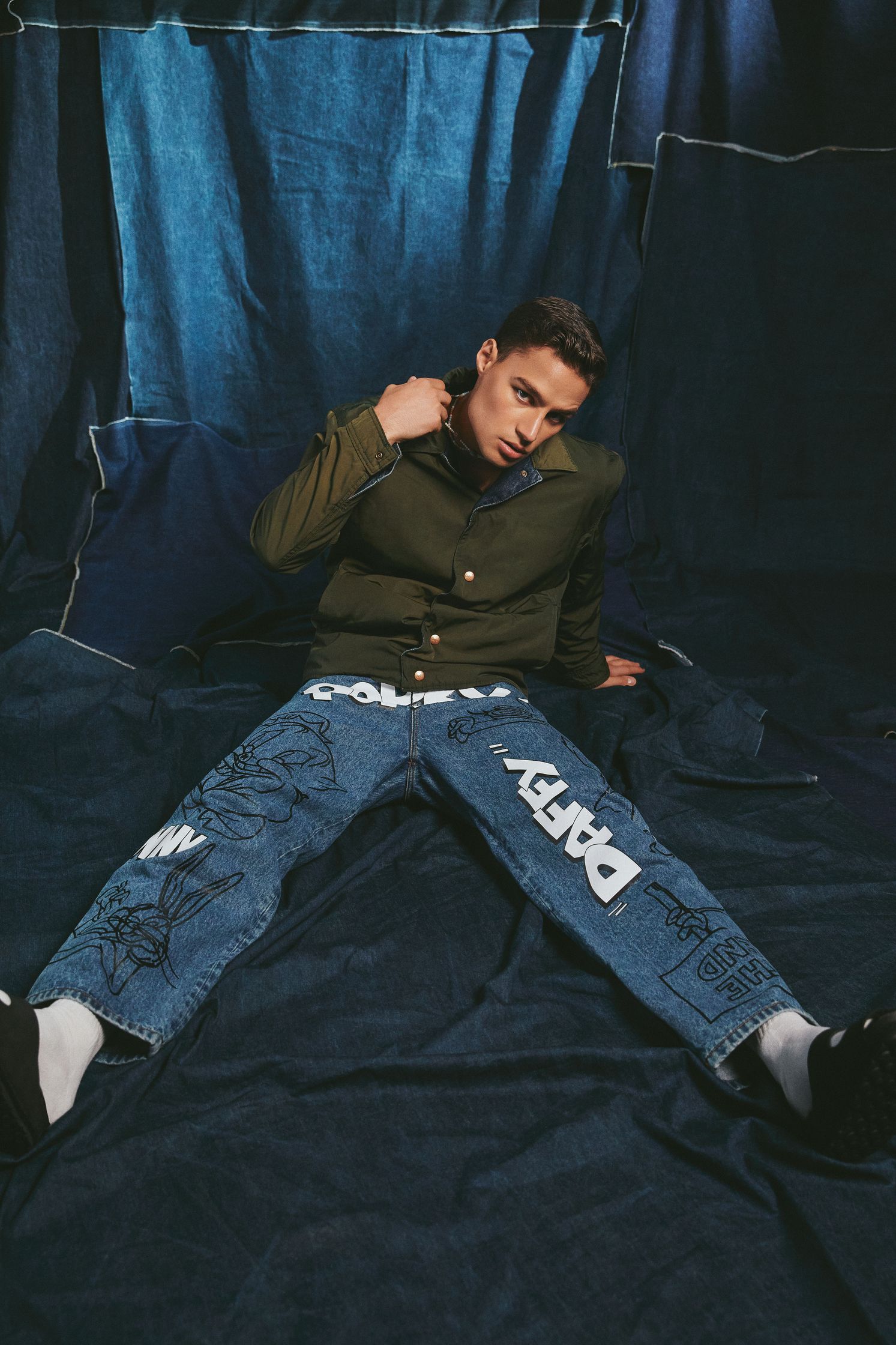 a man laying on a blue blanket with a pair of jeans