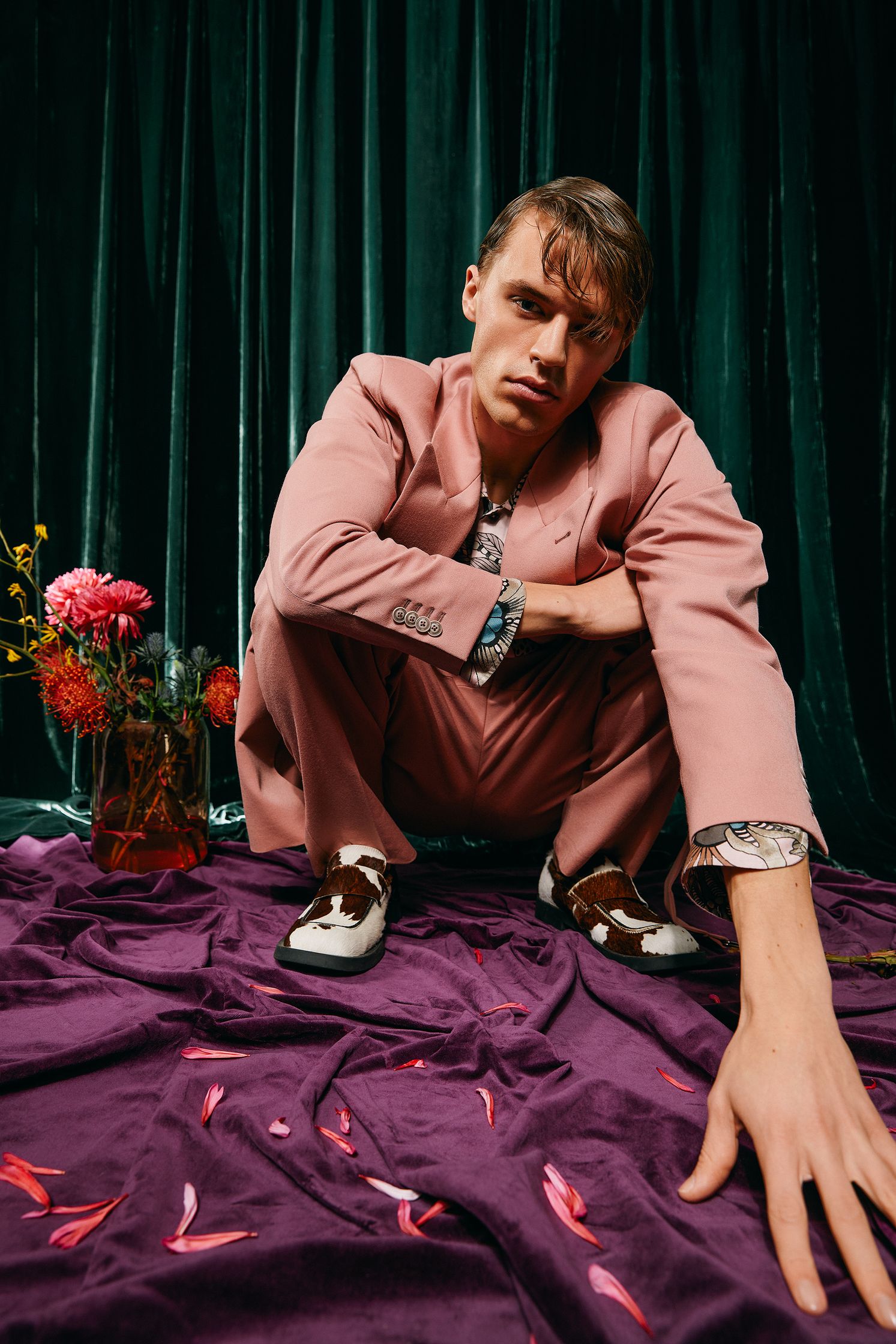 a man in a pink suit kneeling on a purple carpet