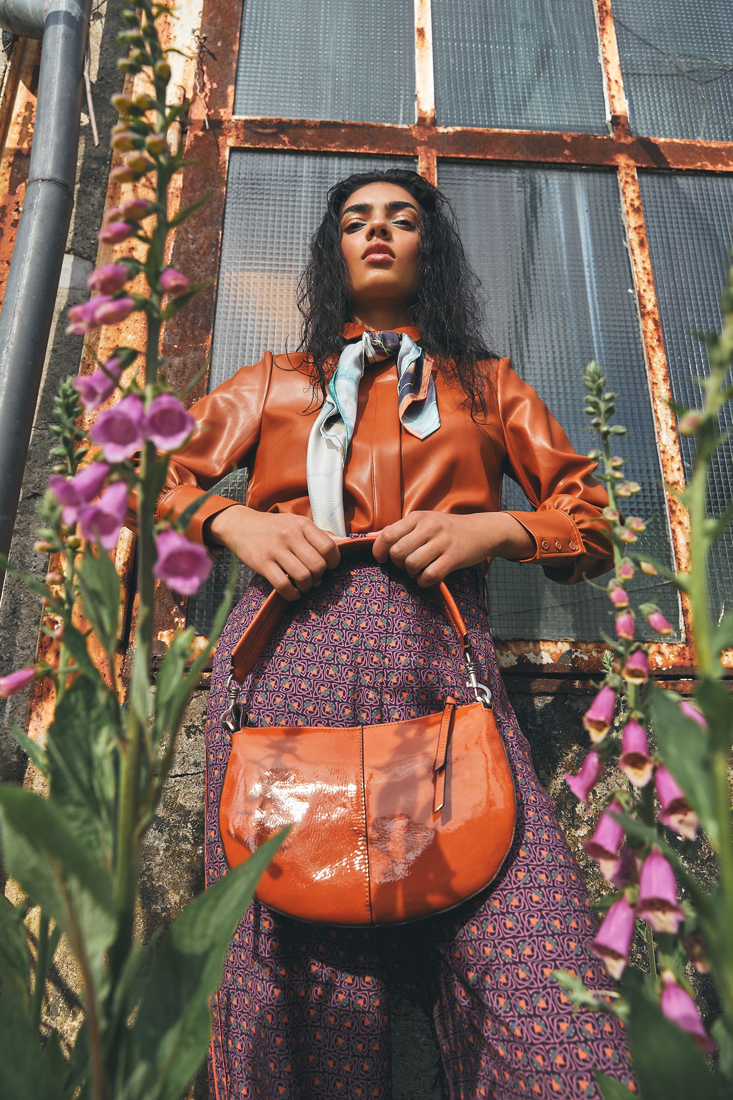 a woman is holding a purse in front of a building