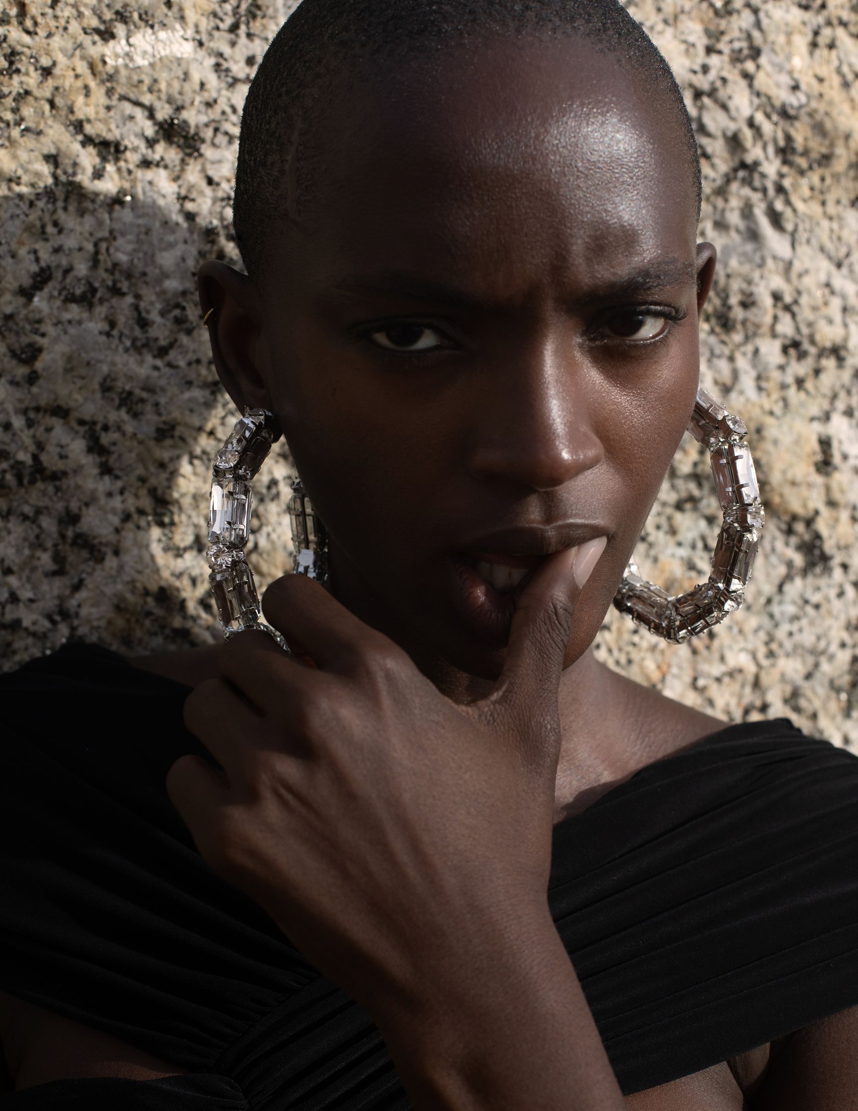 a black woman with a large hoop earring is leaning against a wall