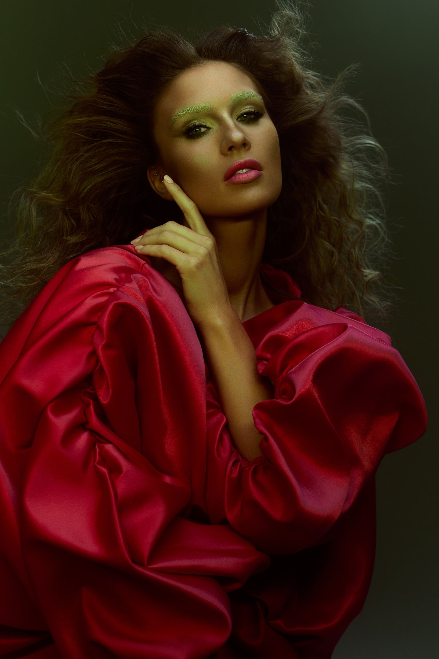 a woman in a red dress posing with her hand on her face