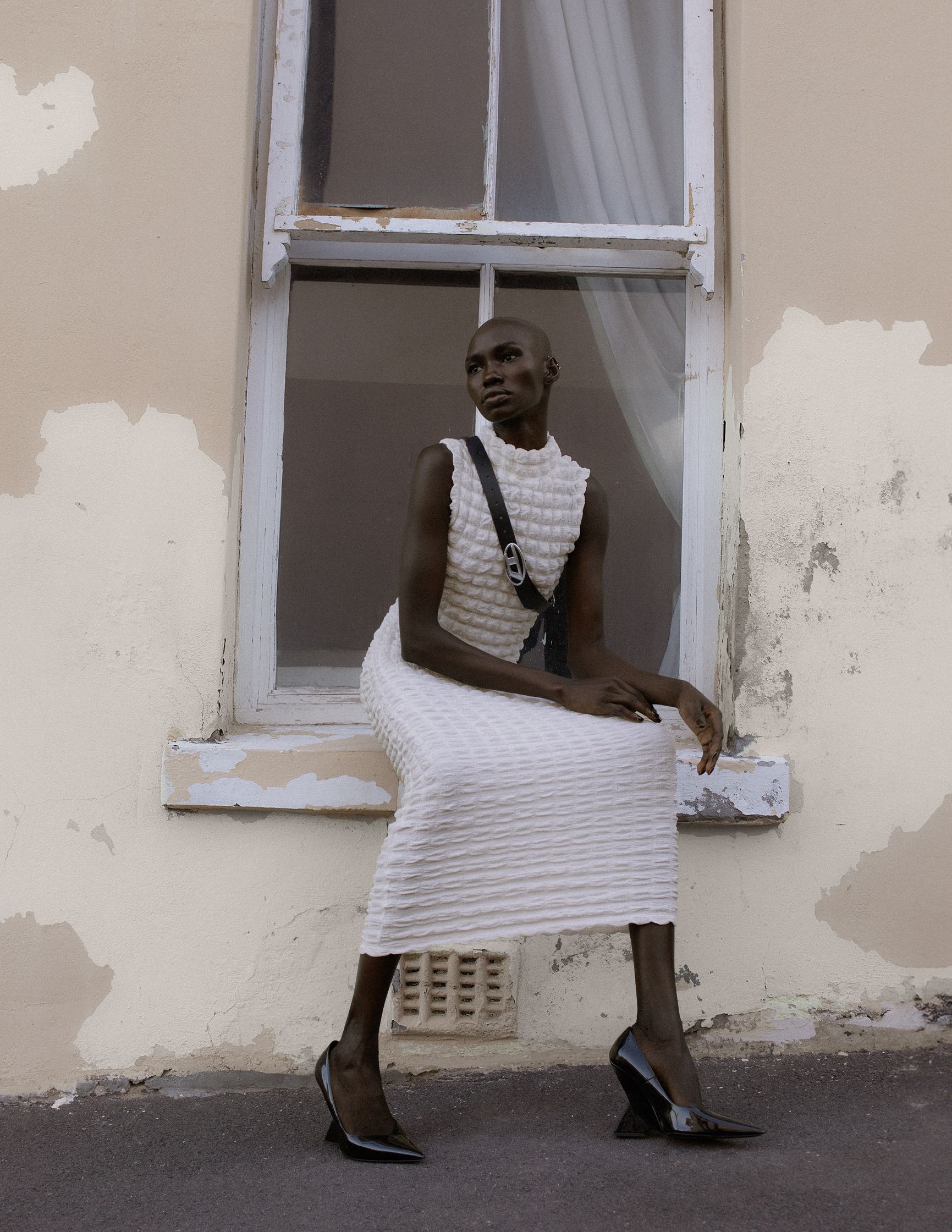 a woman in a white dress leaning against a window
