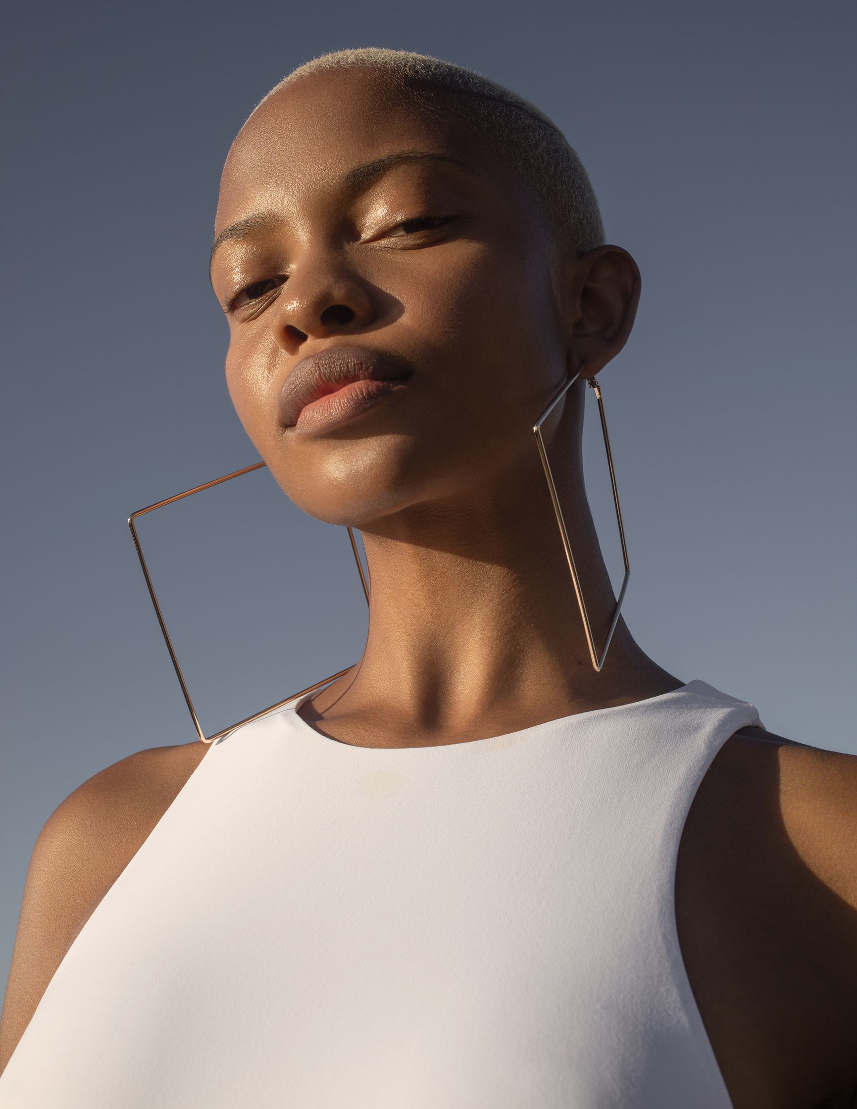 a black woman wearing a white top and hoop earrings