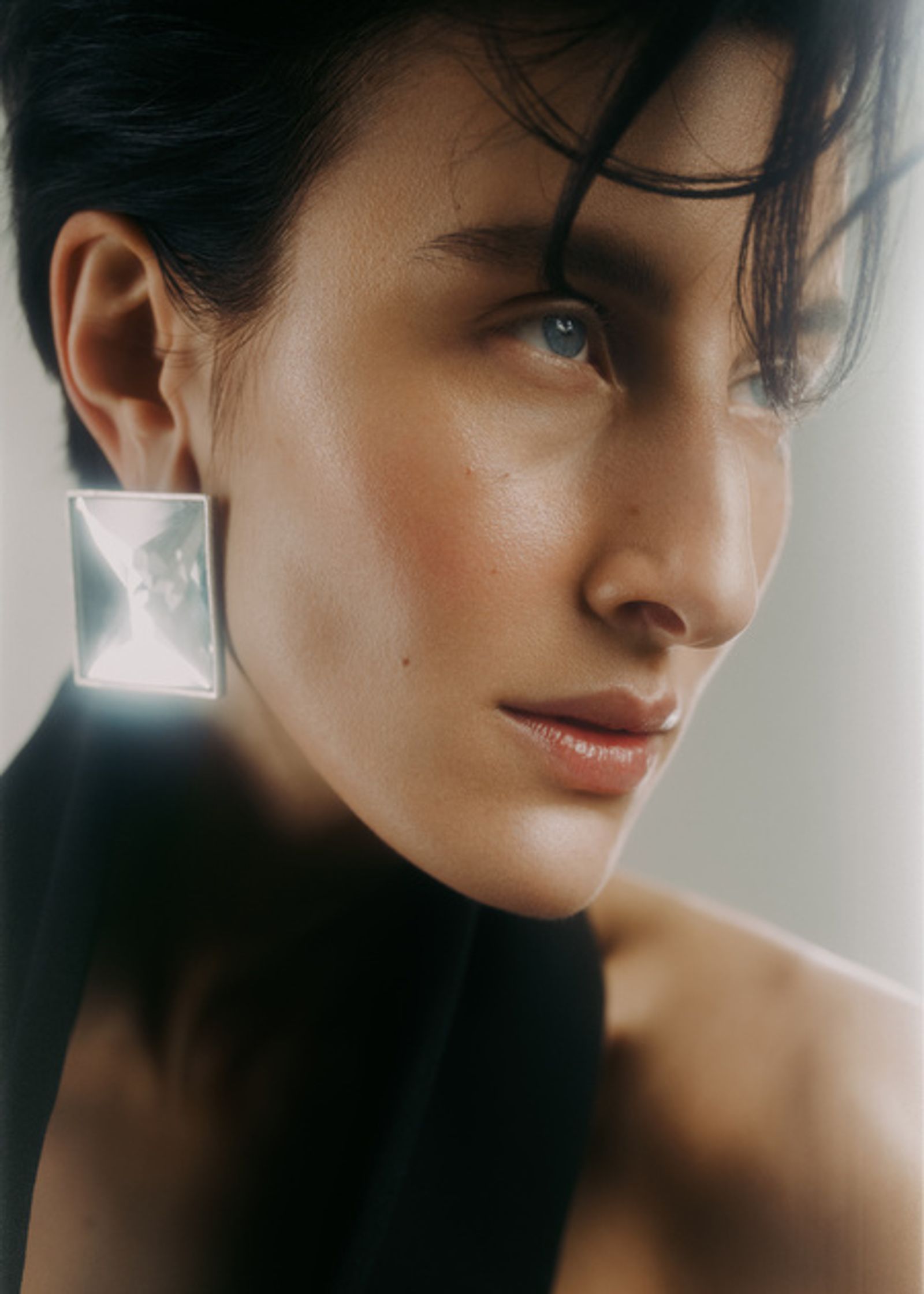 a woman in a black top and a pair of square earrings