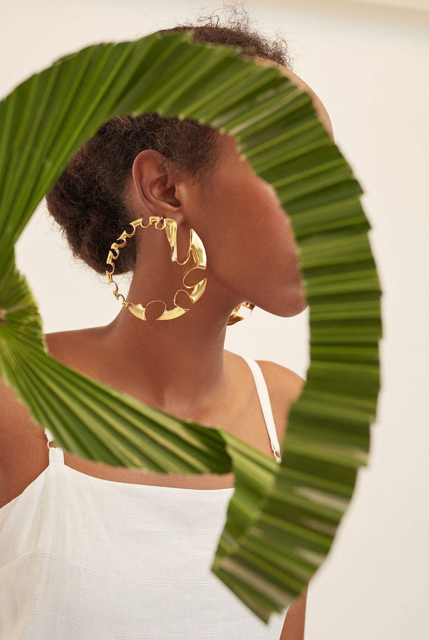 a woman wearing a pair of gold hoop earrings