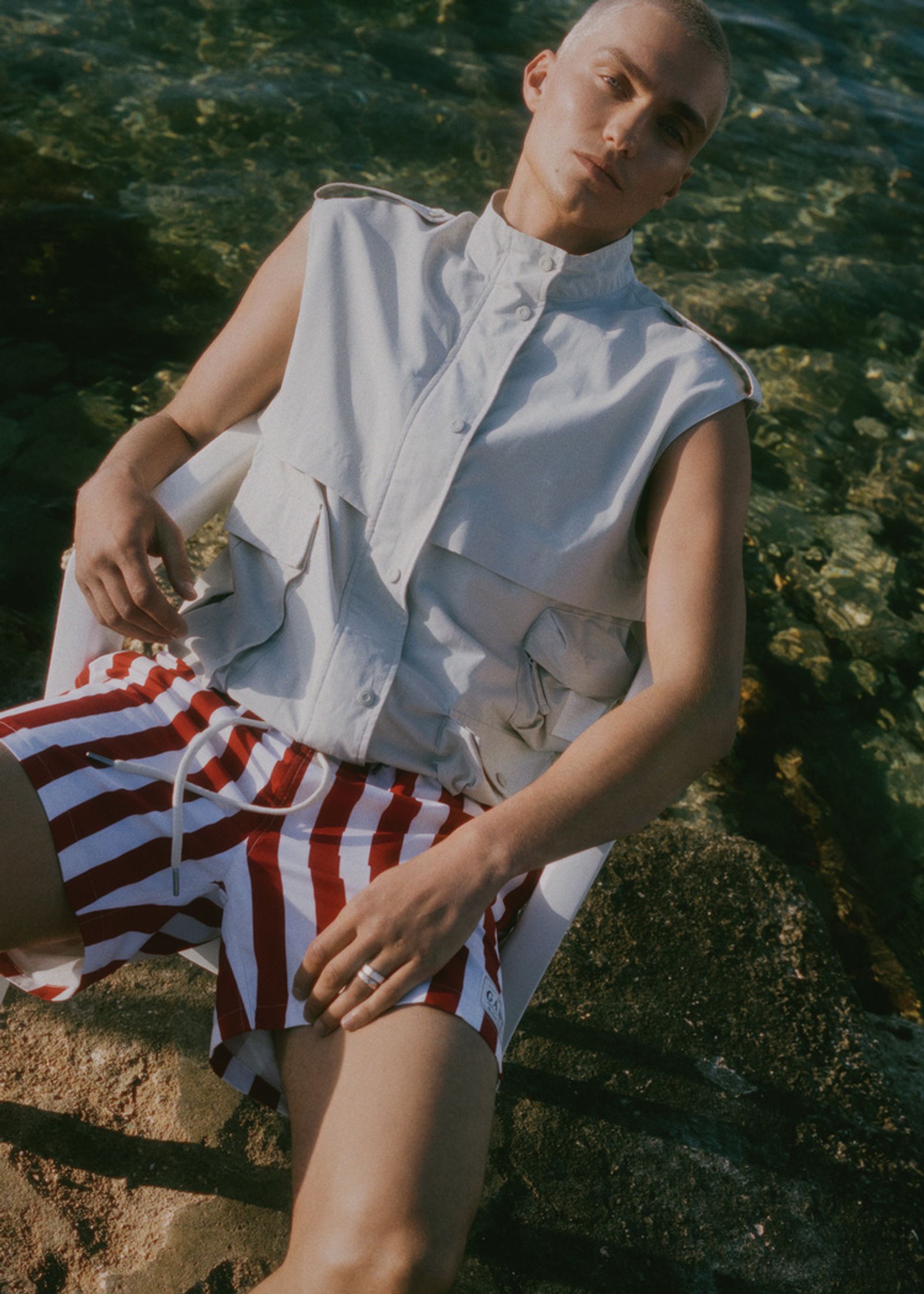 a man in red and white striped shorts sitting on a rock