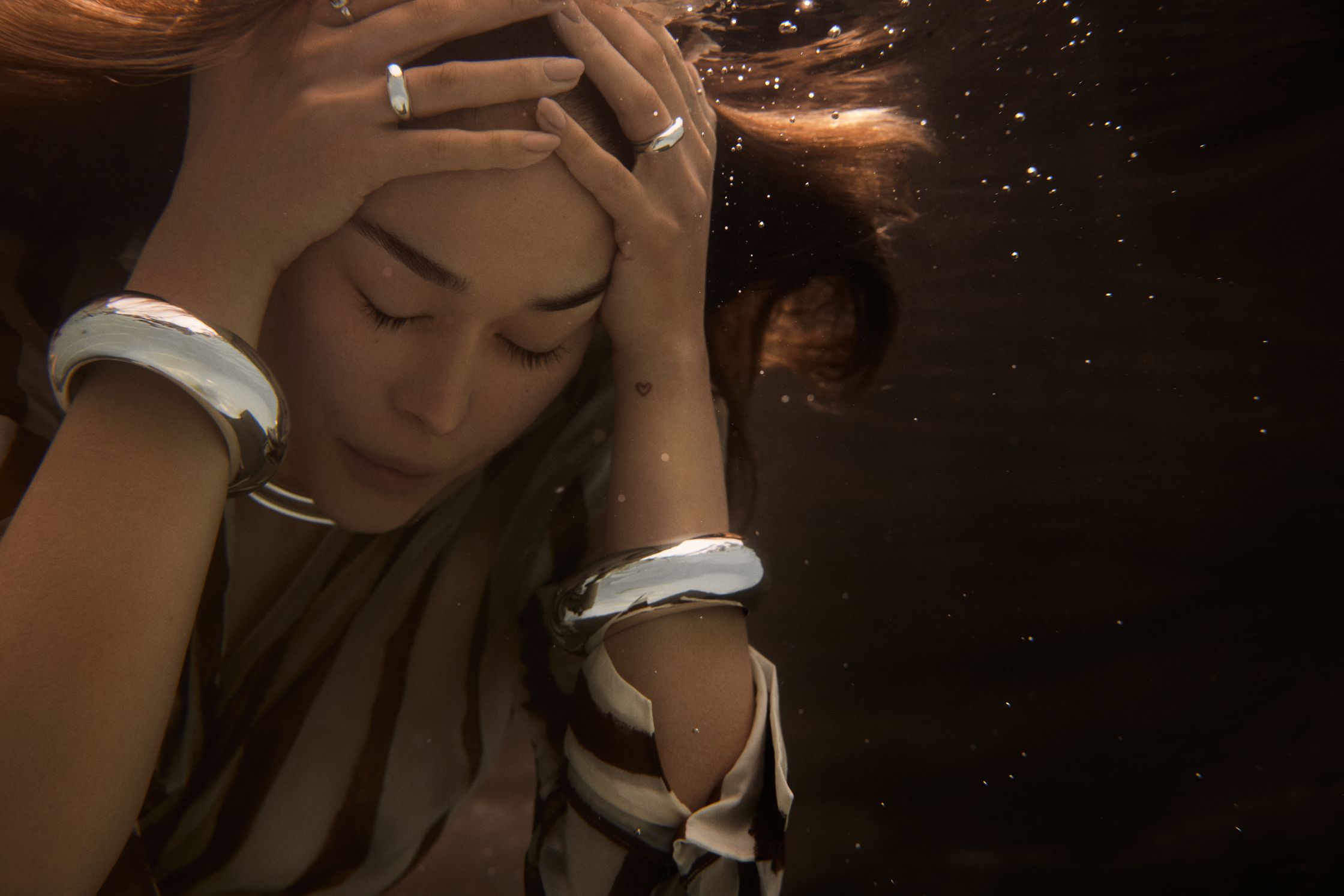 a woman under water with her hands on her head
