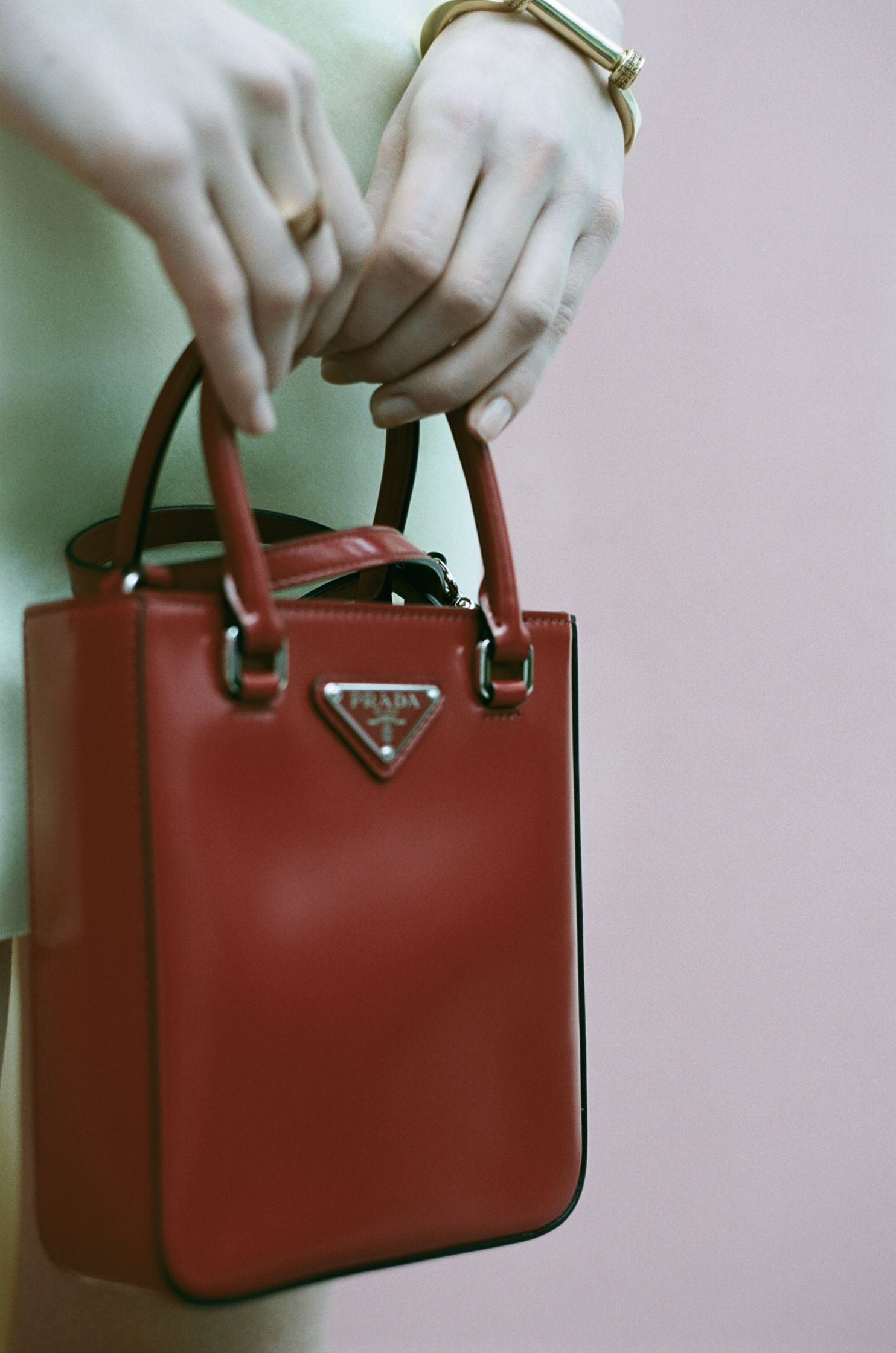 a woman's hand holding a red prada bag