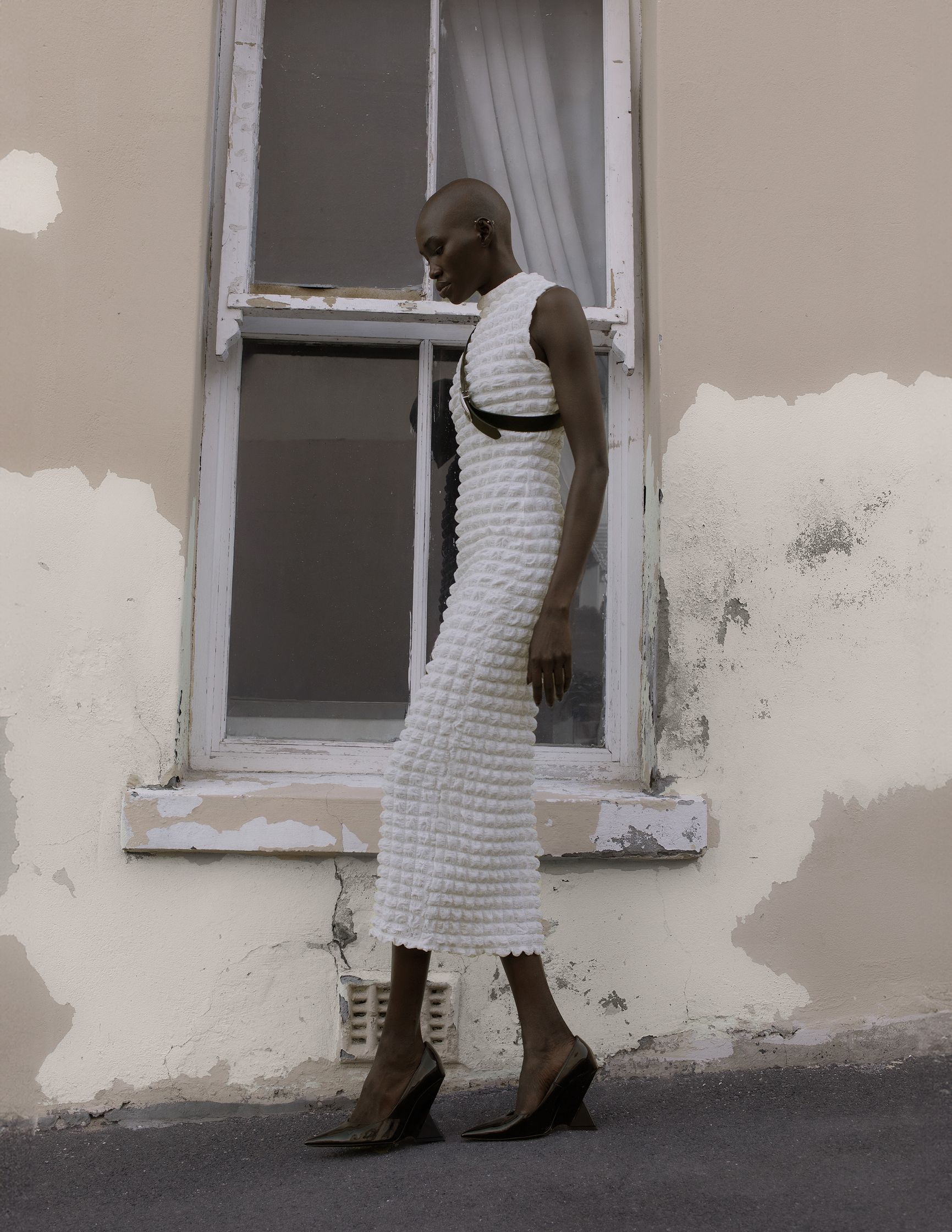 a woman in a white dress standing in front of a window
