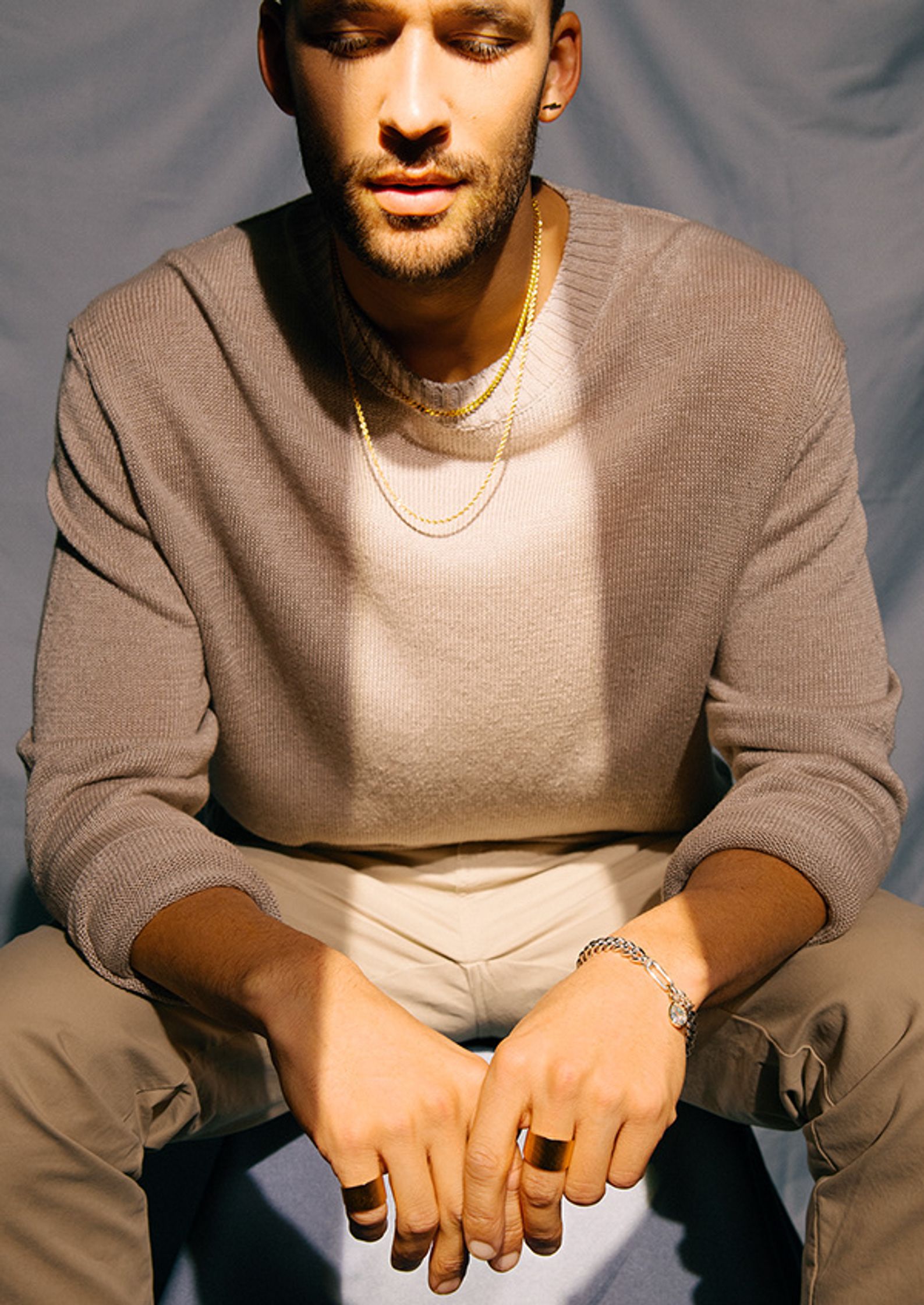 a man sitting on a stool with his hands in his pockets