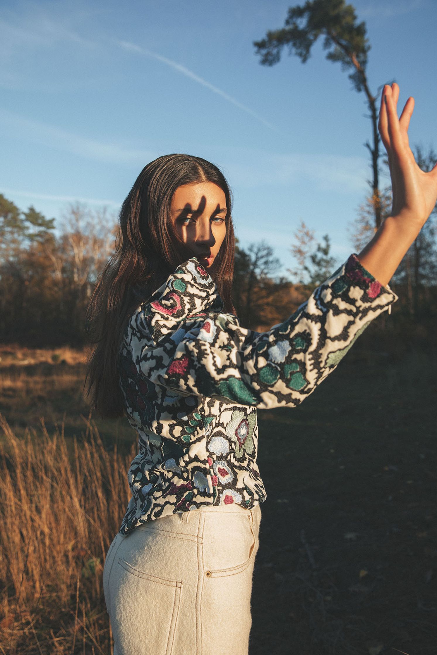 a woman is standing in a field with her hands up