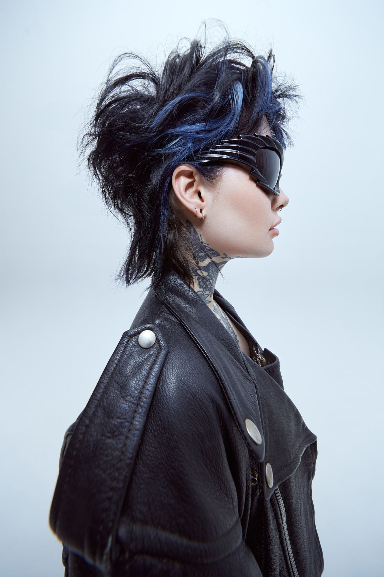 a woman with blue hair in a leather jacket and sunglasses