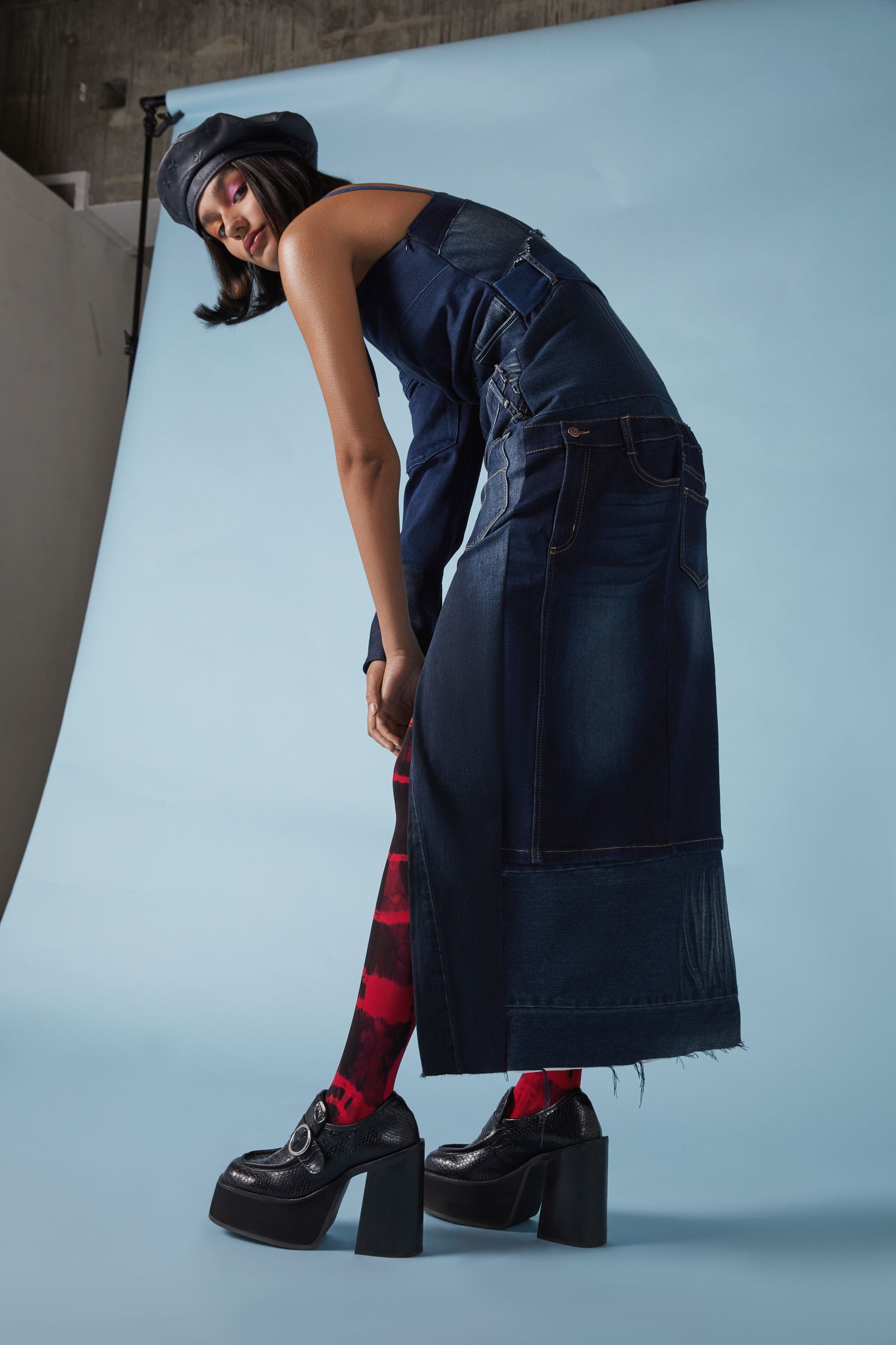 a woman in a denim overall dress posing for a photo
