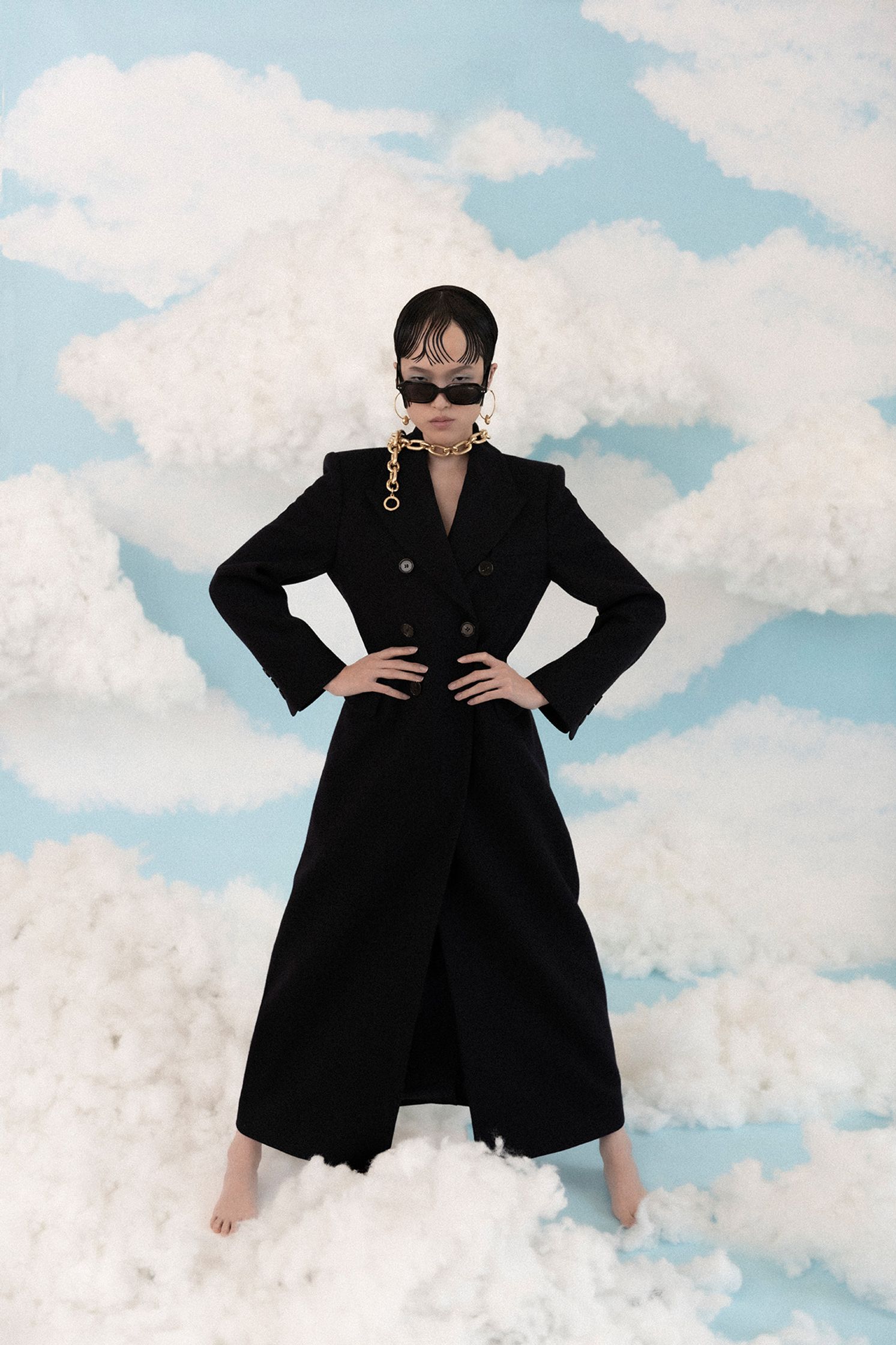 a woman in a black coat posing on clouds