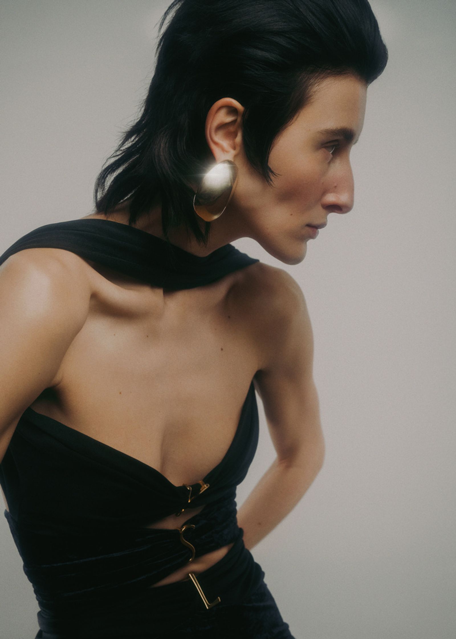 a woman in a black dress with gold earrings