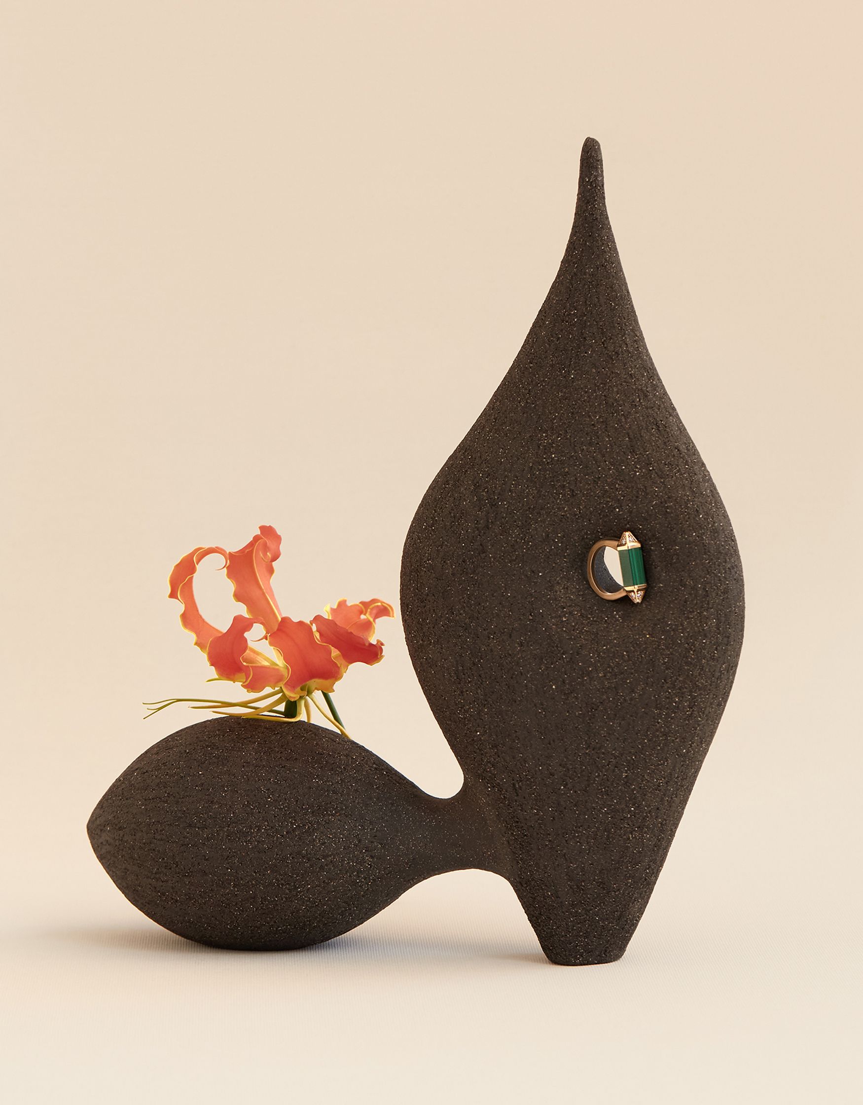 a black vase with a flower in it