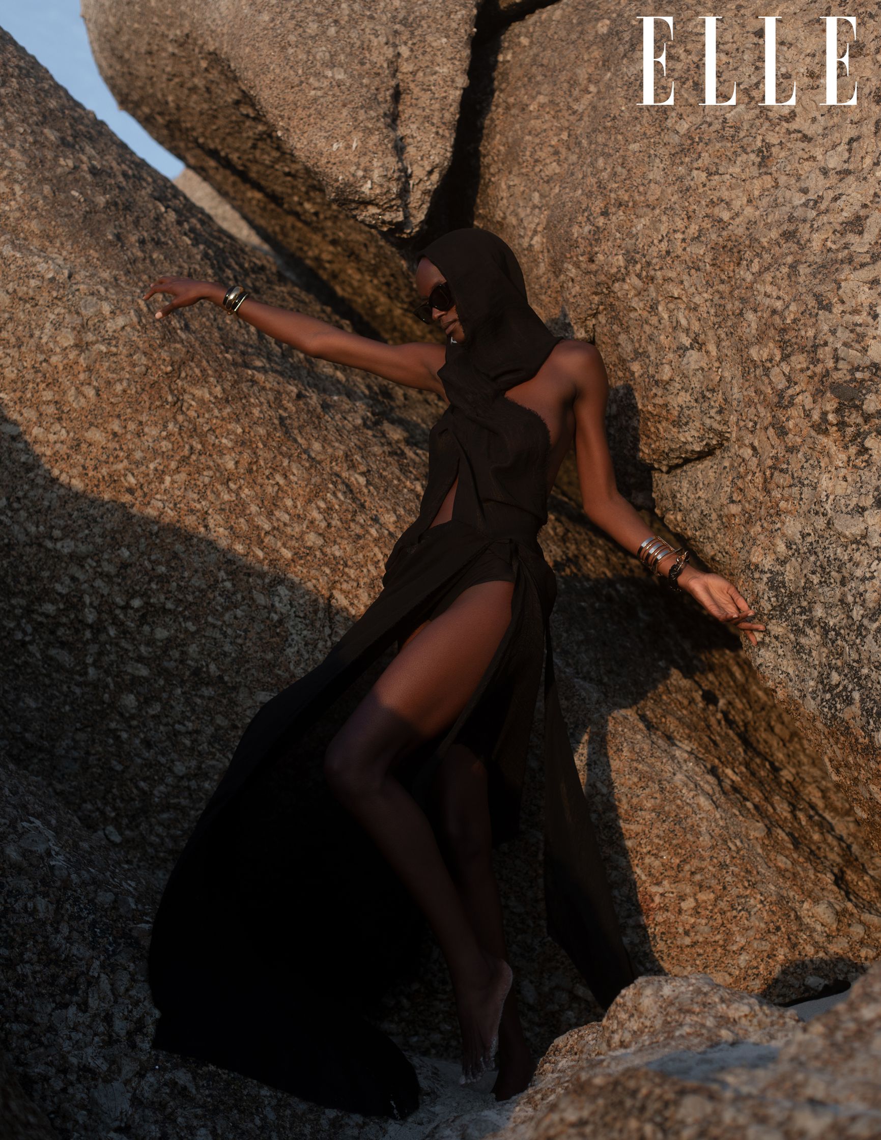 a woman in a black dress standing on rocks