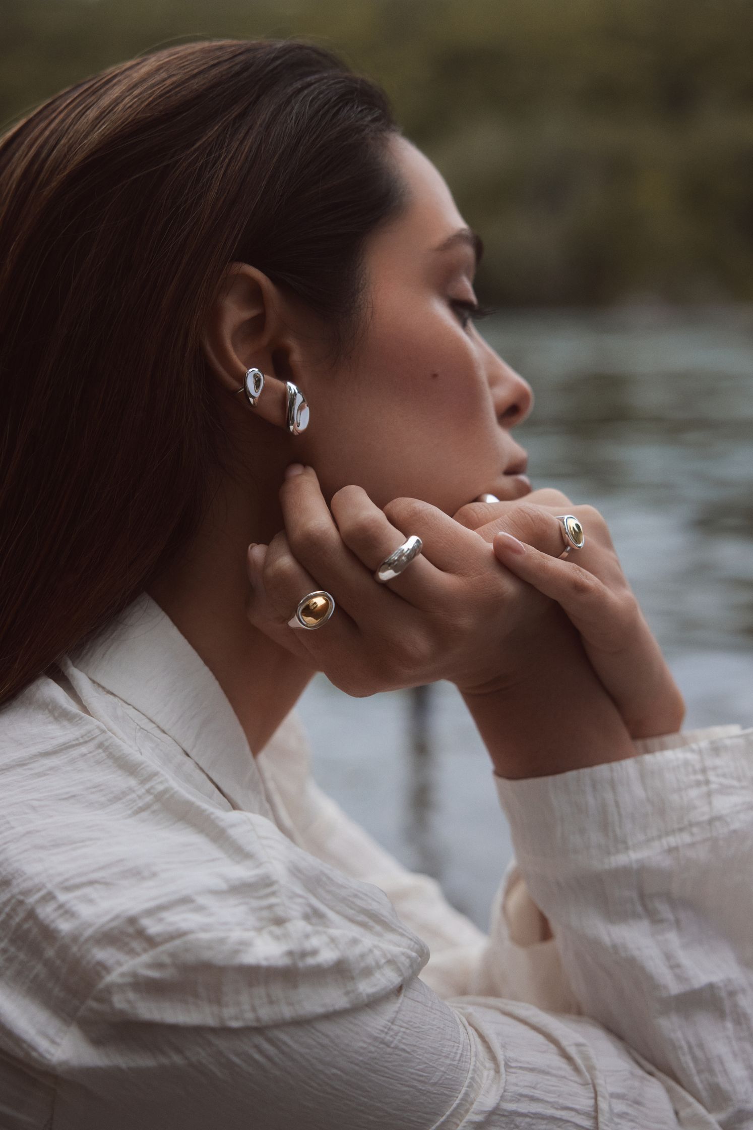 a woman wearing a white shirt and a pair of earrings