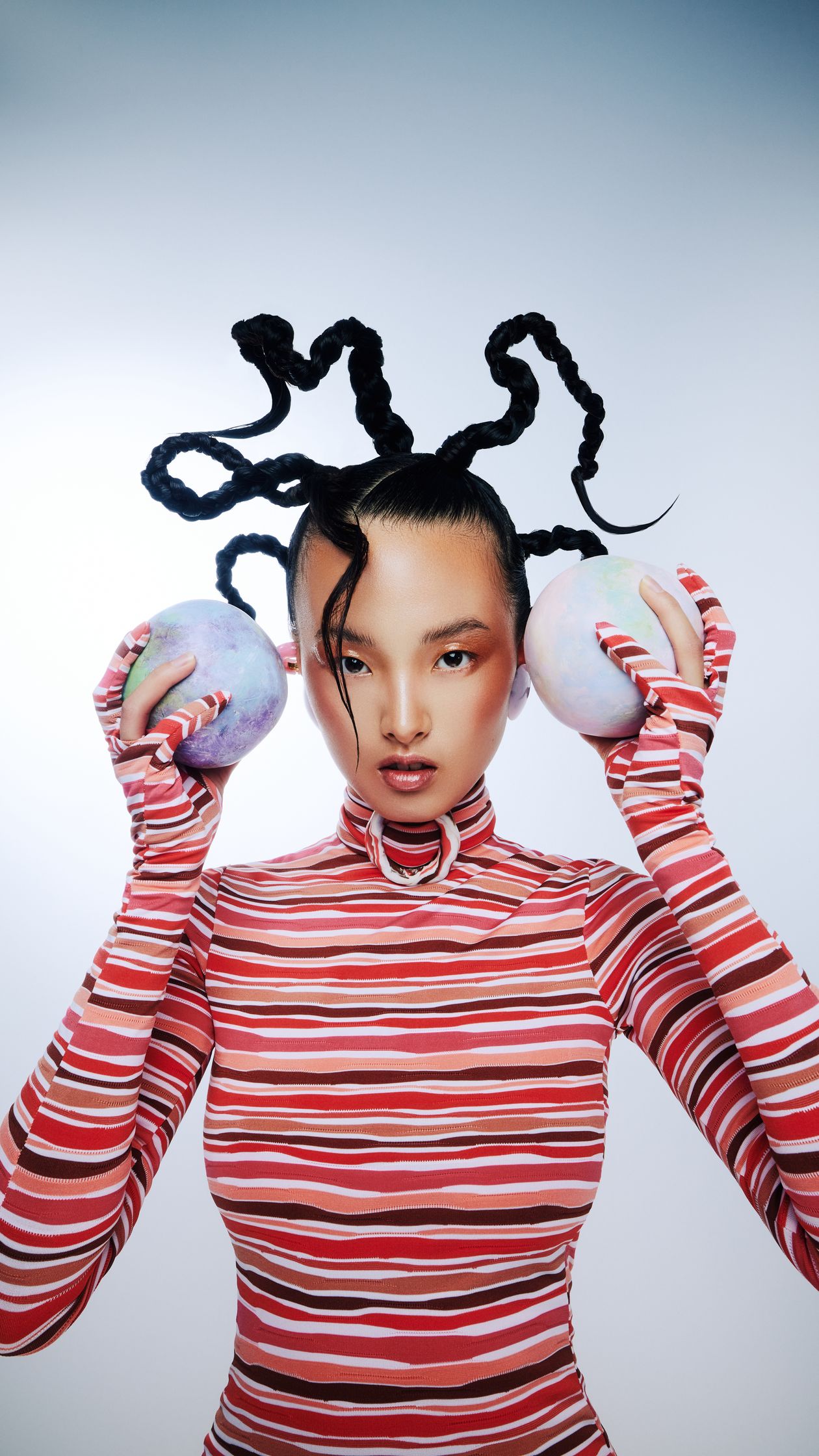 a woman with dreadlocks holding two balls in her hands