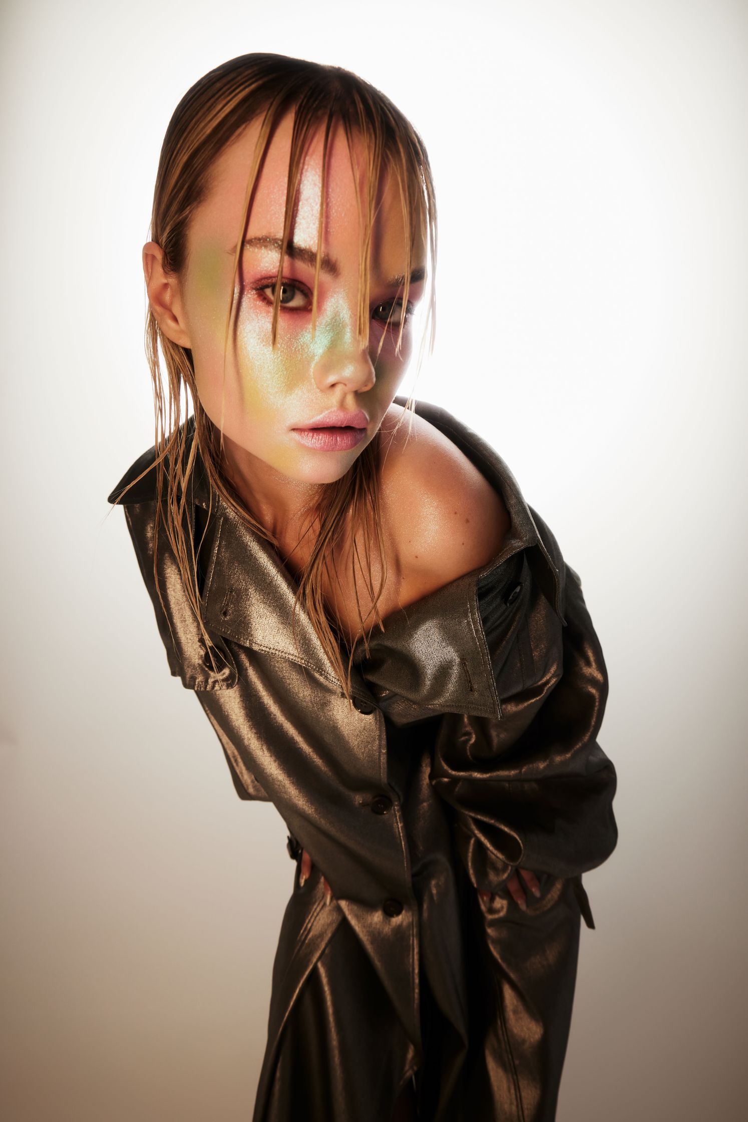a woman in a metallic coat posing in front of a white background