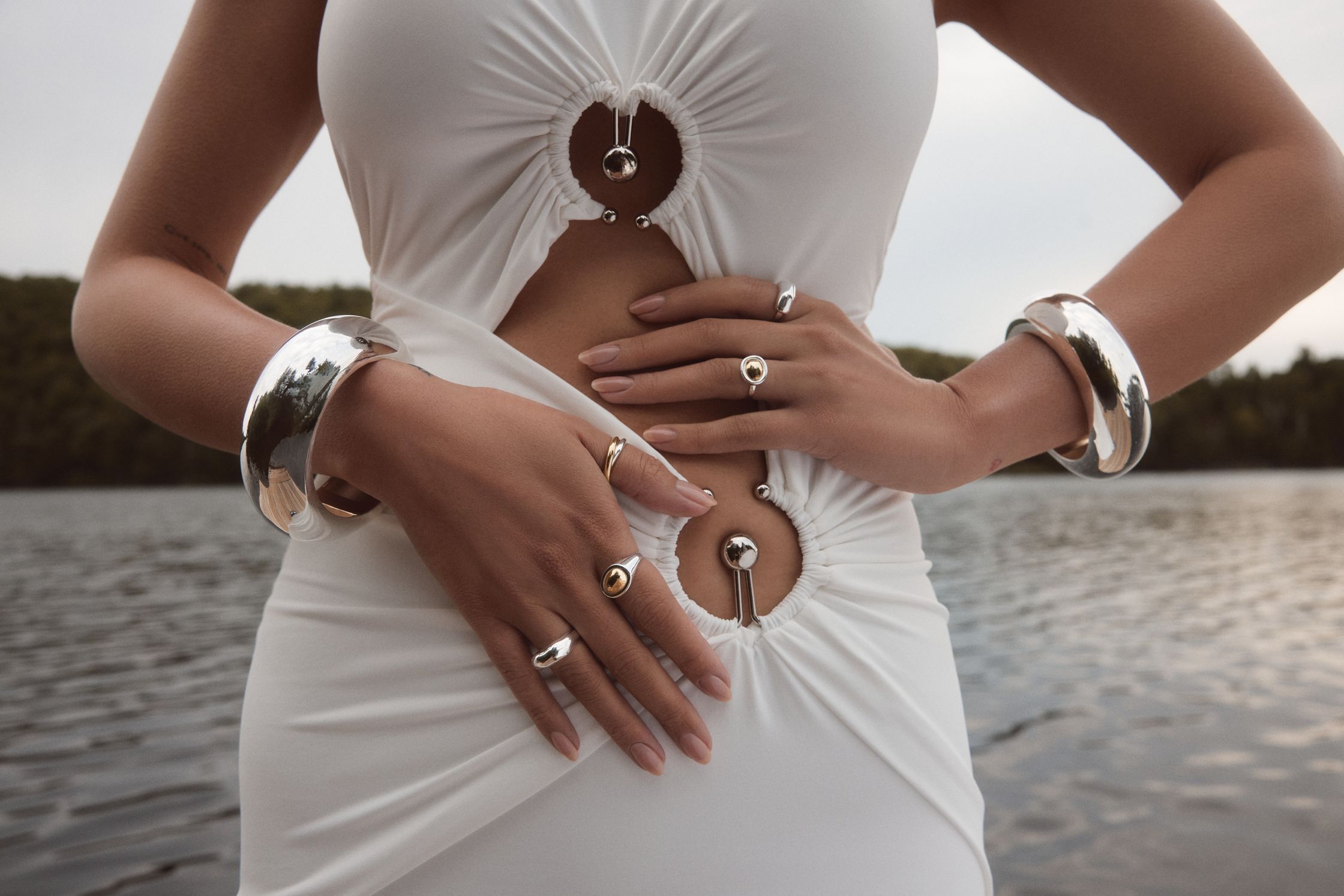 a woman wearing a white dress and silver rings
