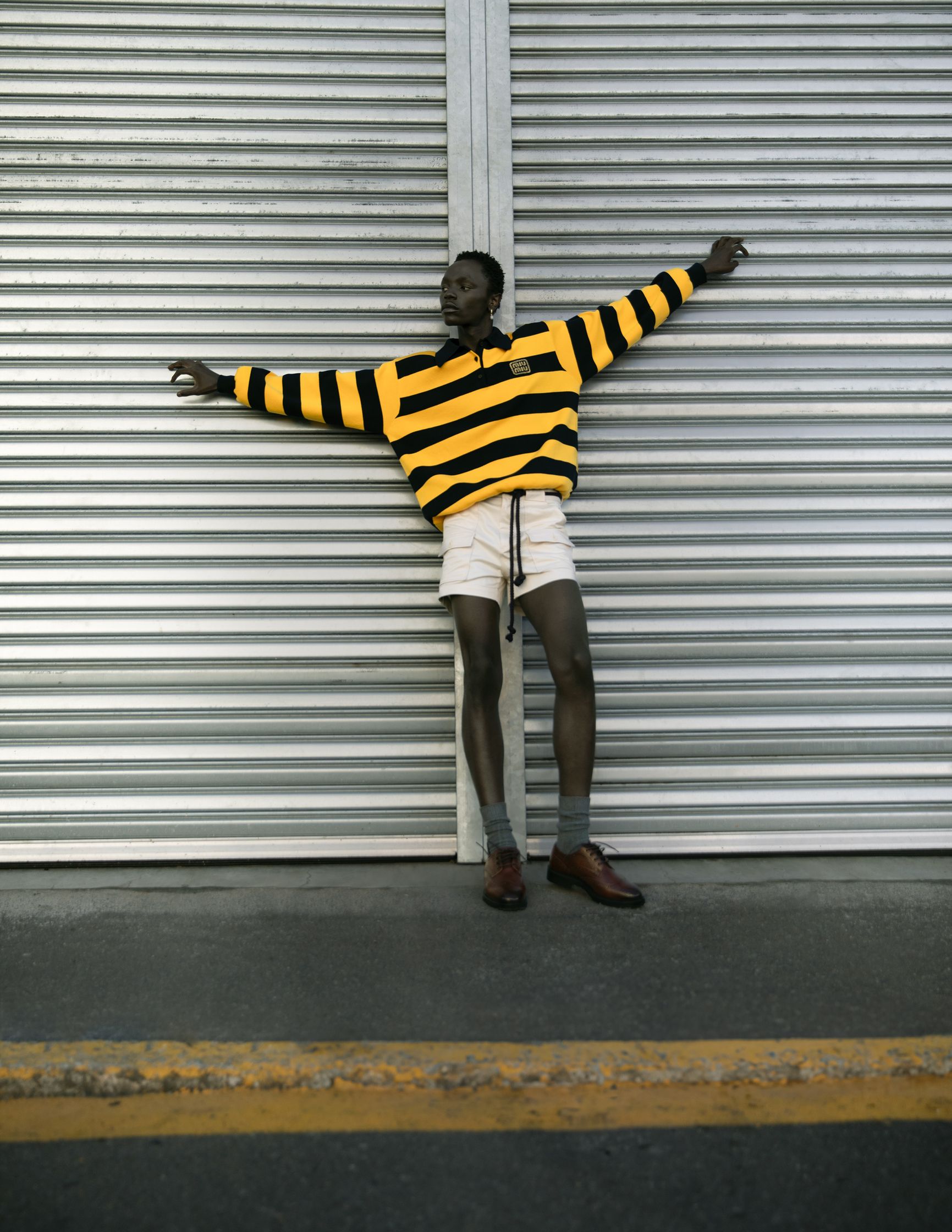 a man in a yellow and black striped sweater leaning against a metal door