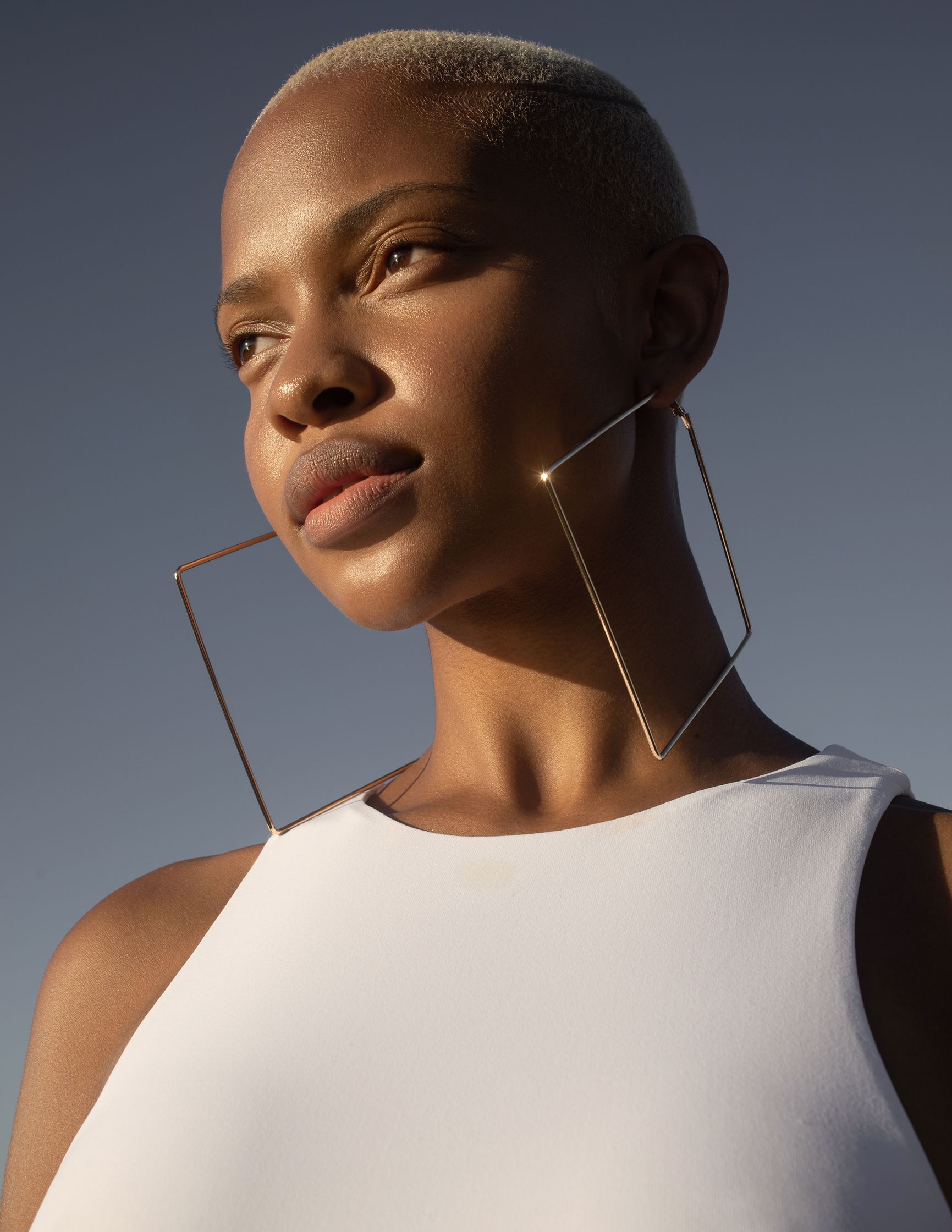 a black woman wearing a white top and gold hoop earrings