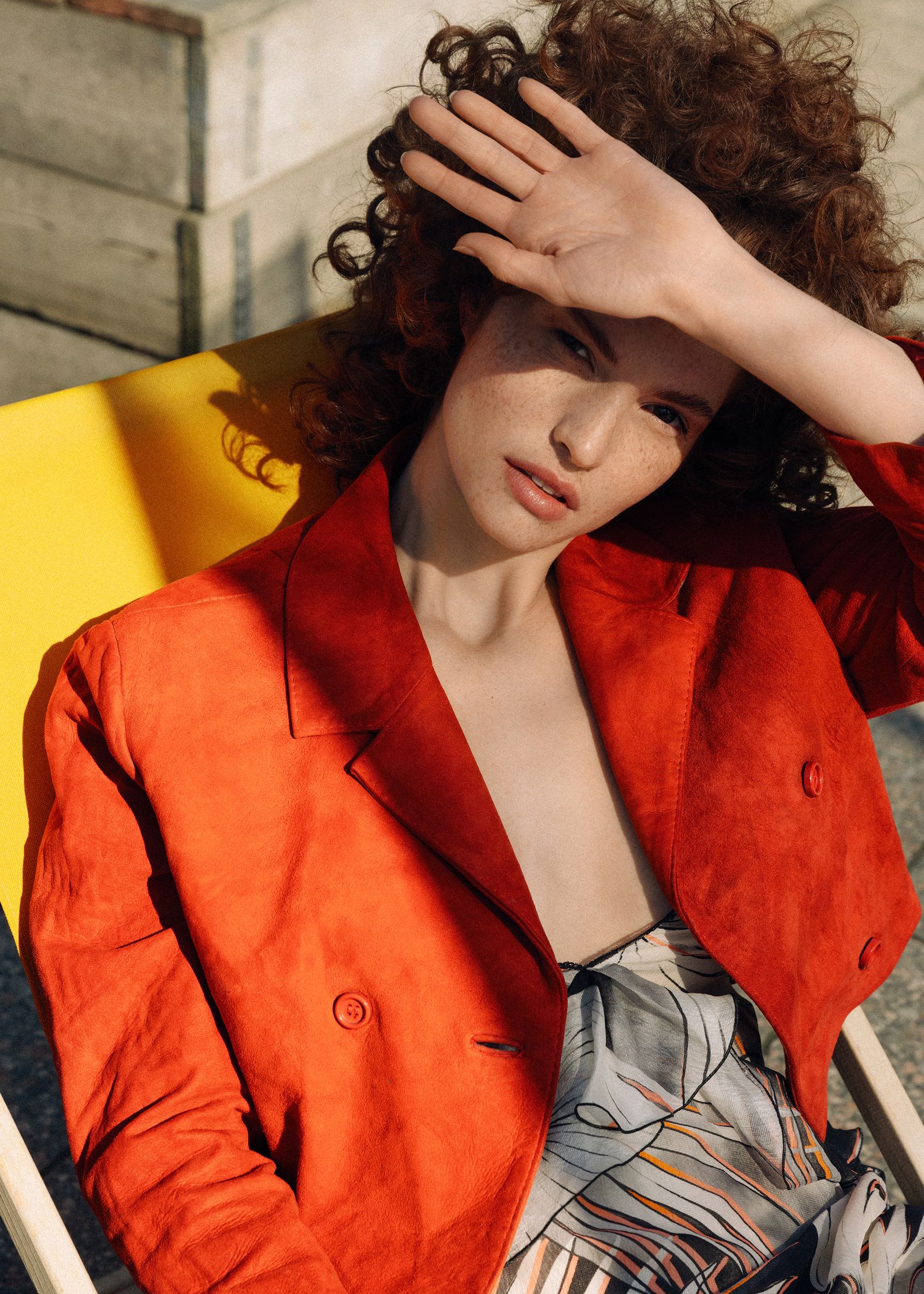 a woman in a red jacket sitting on a yellow chair