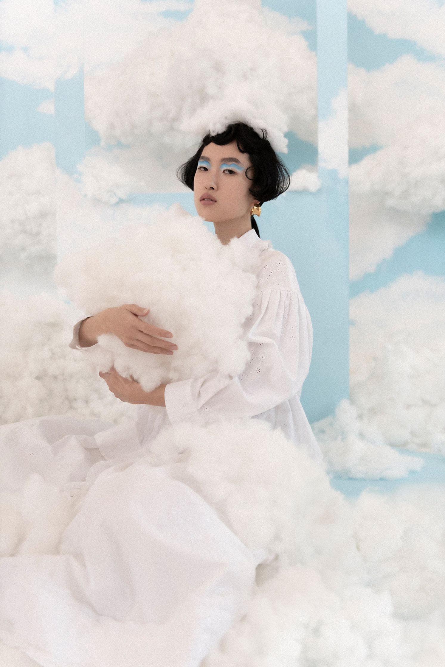 a woman in a white dress sitting on top of clouds