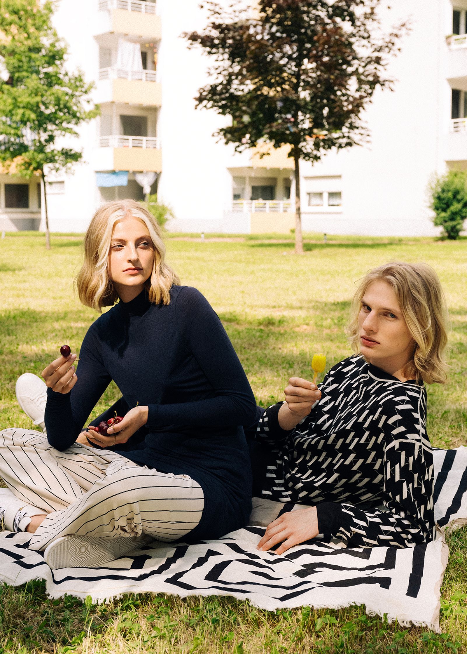 two women sitting on a blanket in the grass