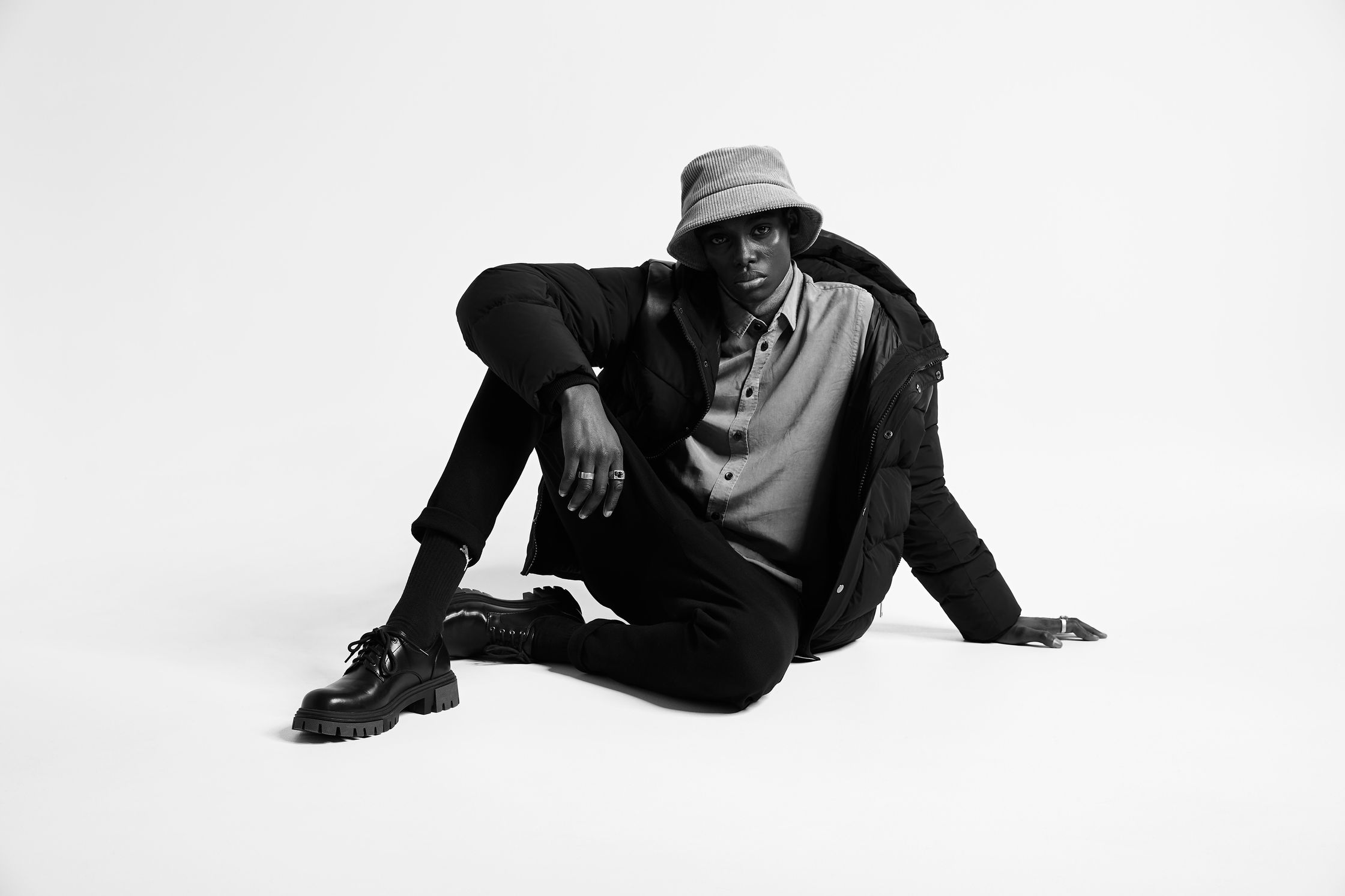 a black man in a hat sitting on the ground