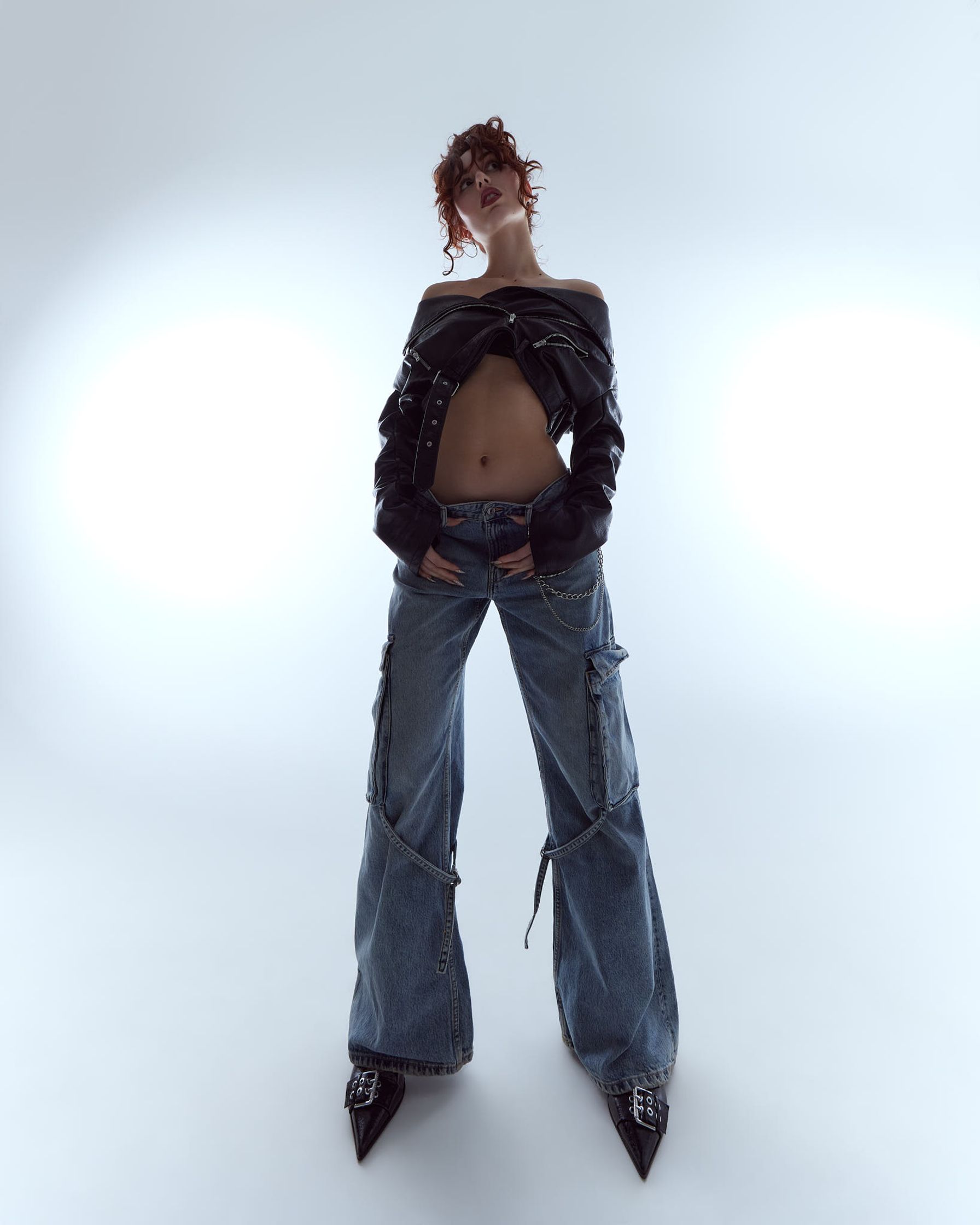 a woman in jeans and a jacket posing on a white background