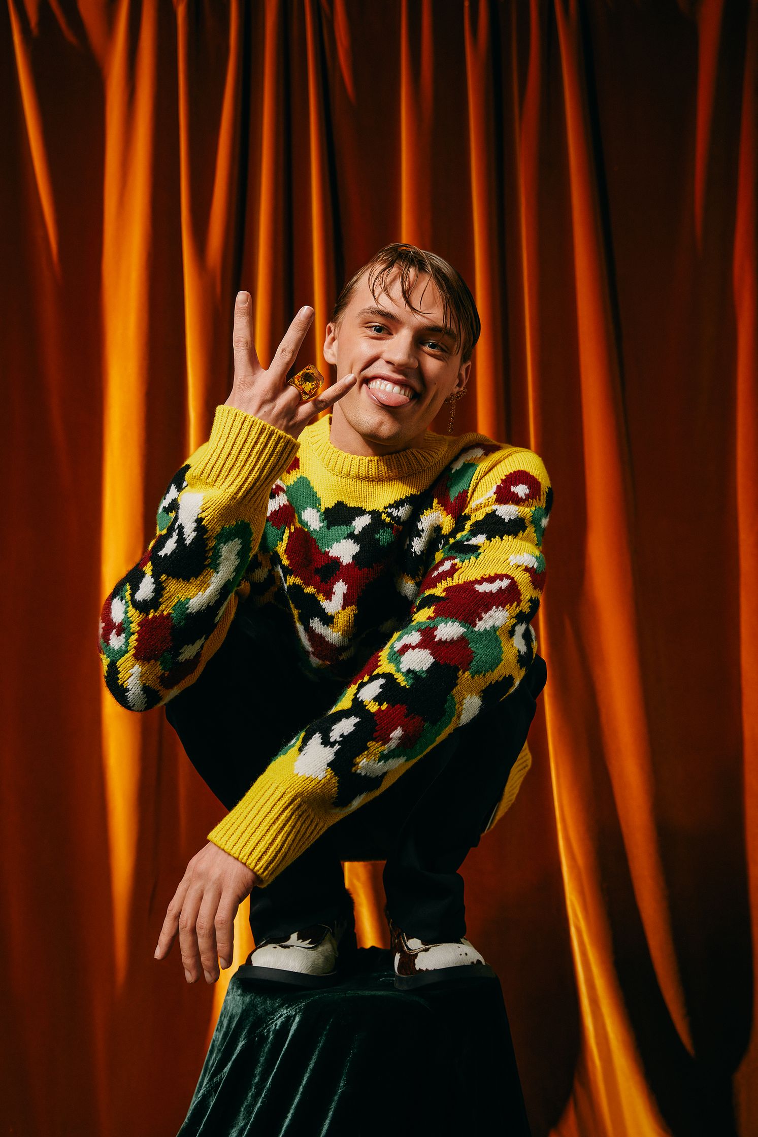 a man in a colorful sweater posing for the camera