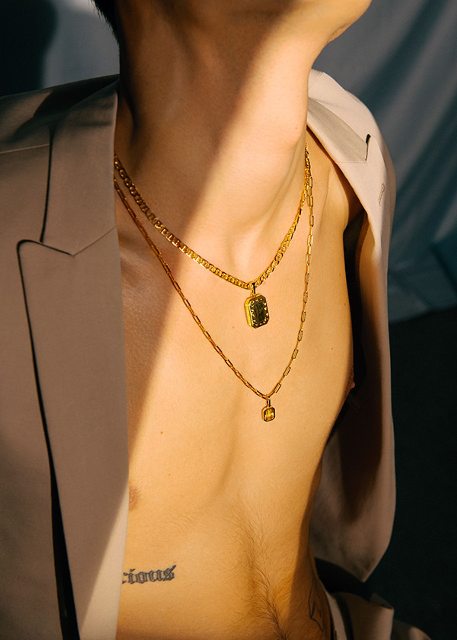 a man in a suit with a gold chain necklace