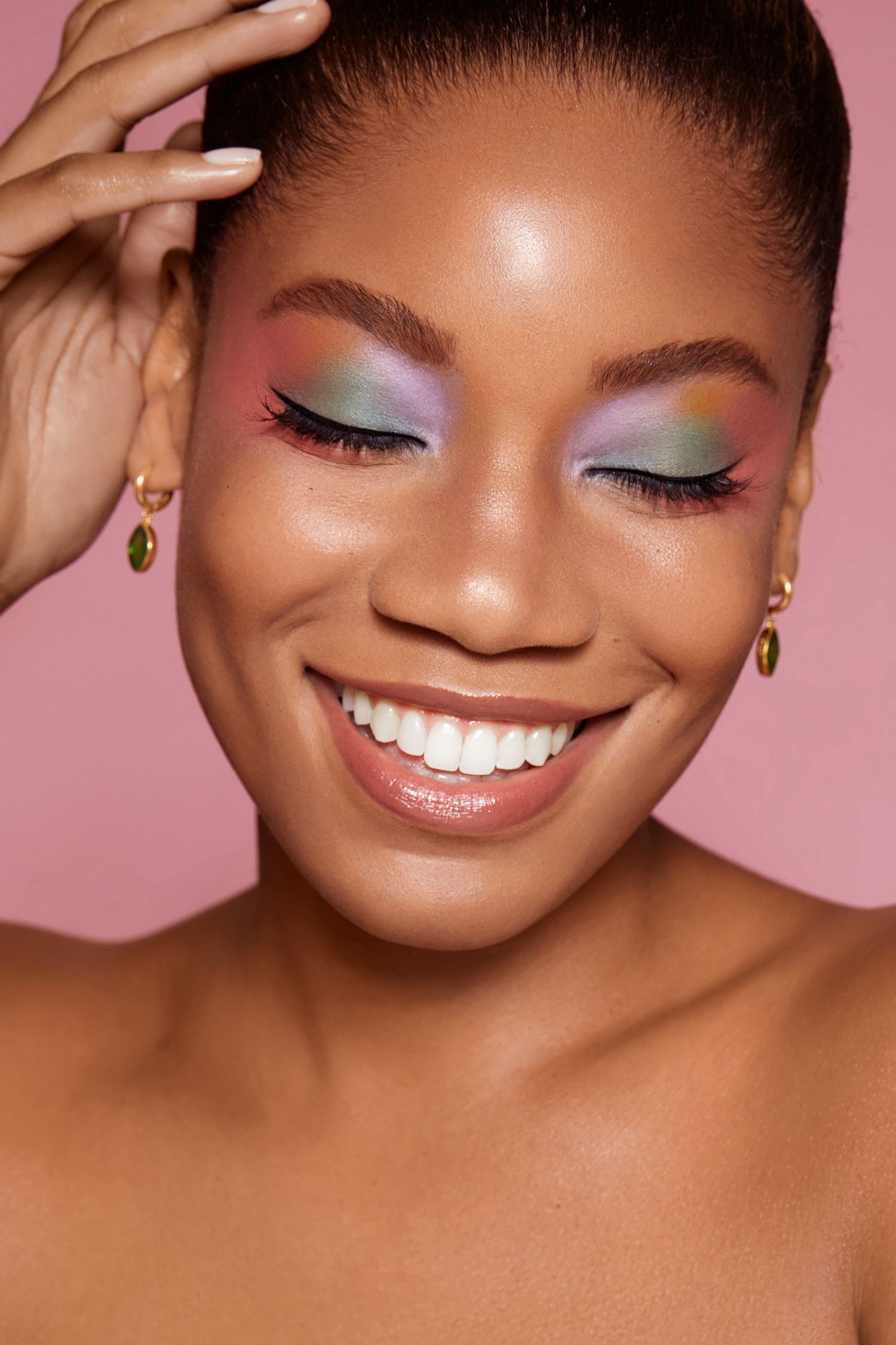 a black woman smiling with colorful makeup on her face