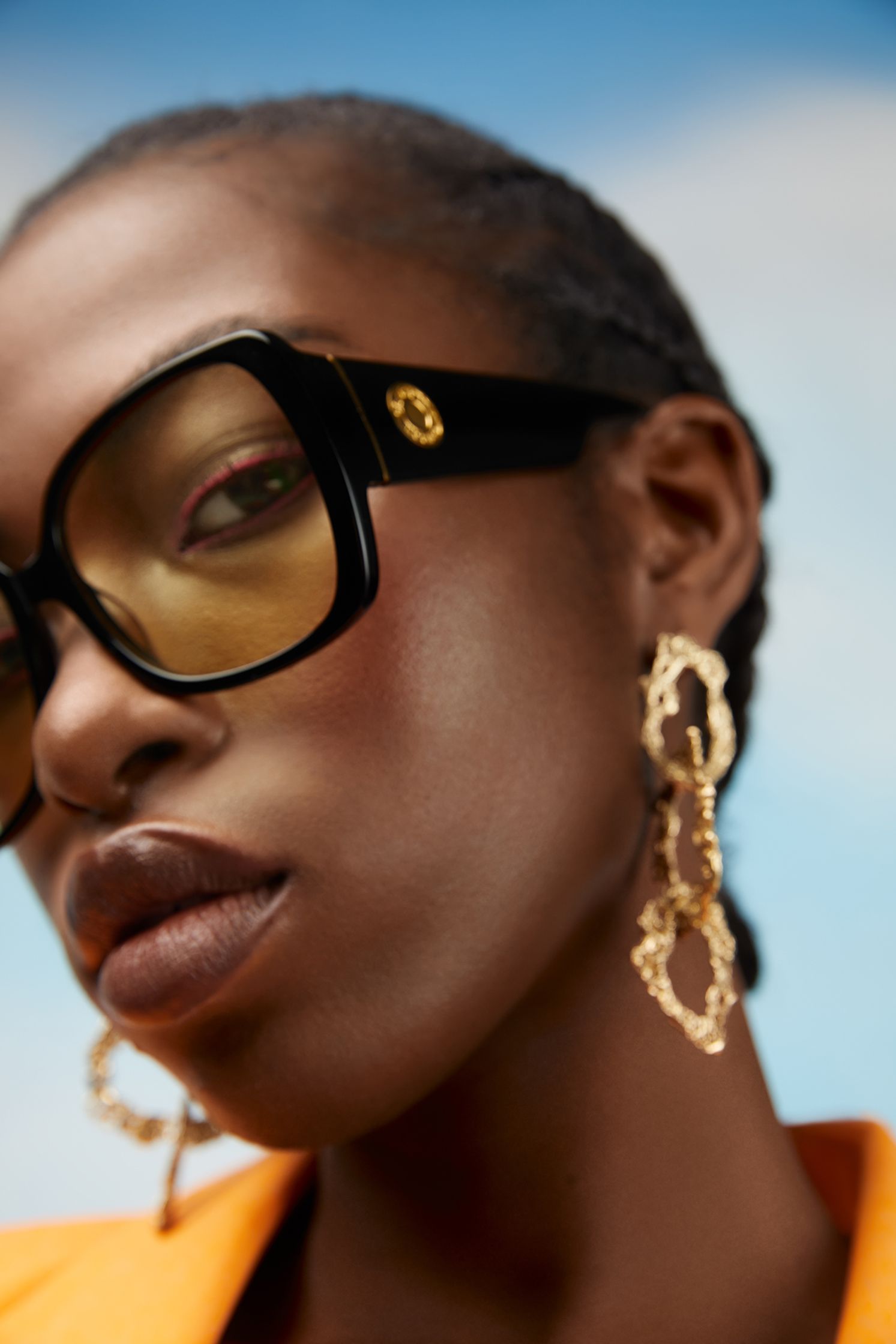 a black woman wearing sunglasses and gold earrings
