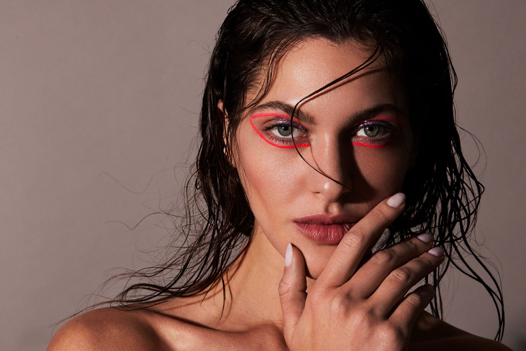 a woman with red eye makeup posing with her hand on her face