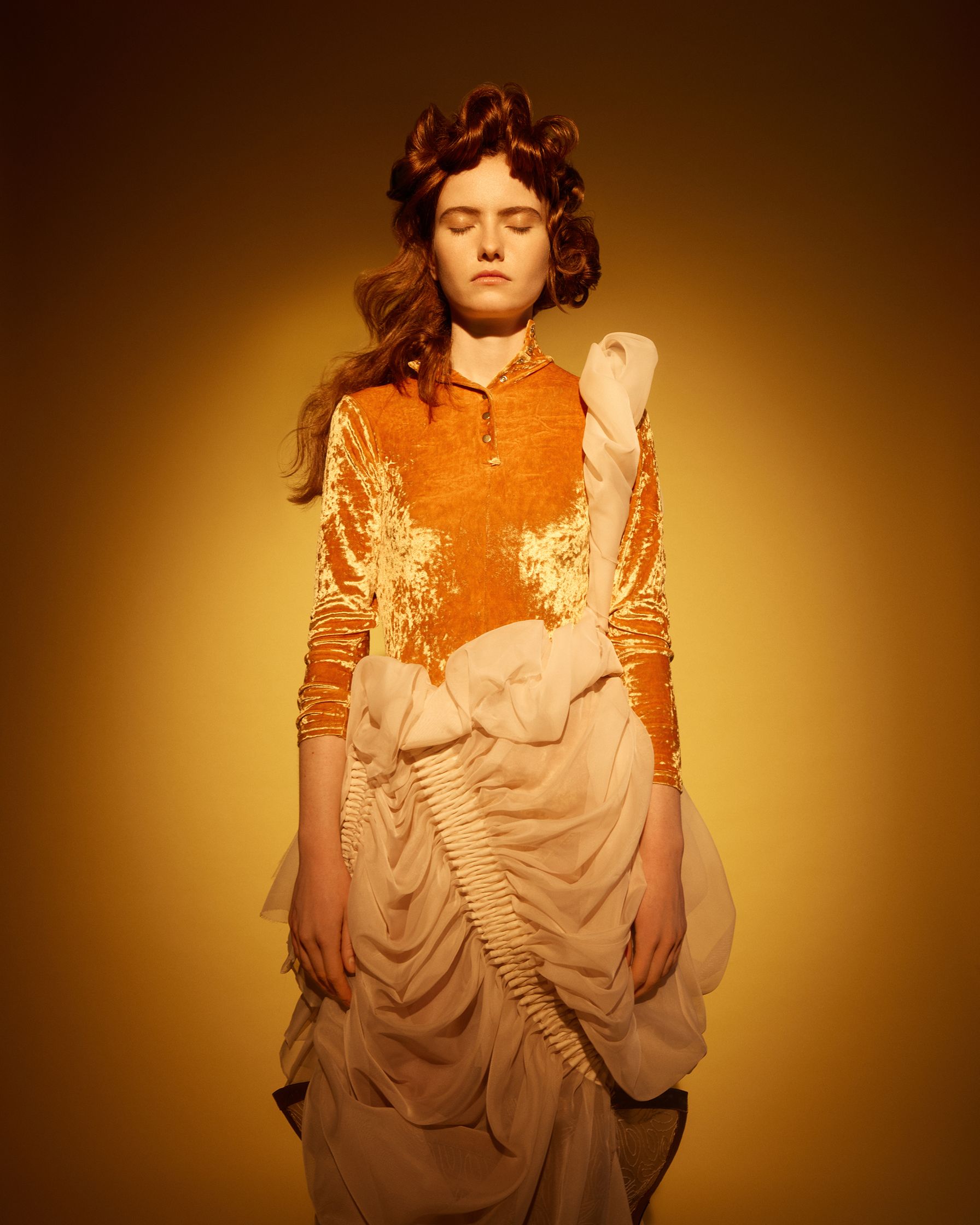 a woman in an orange dress standing in front of a yellow background