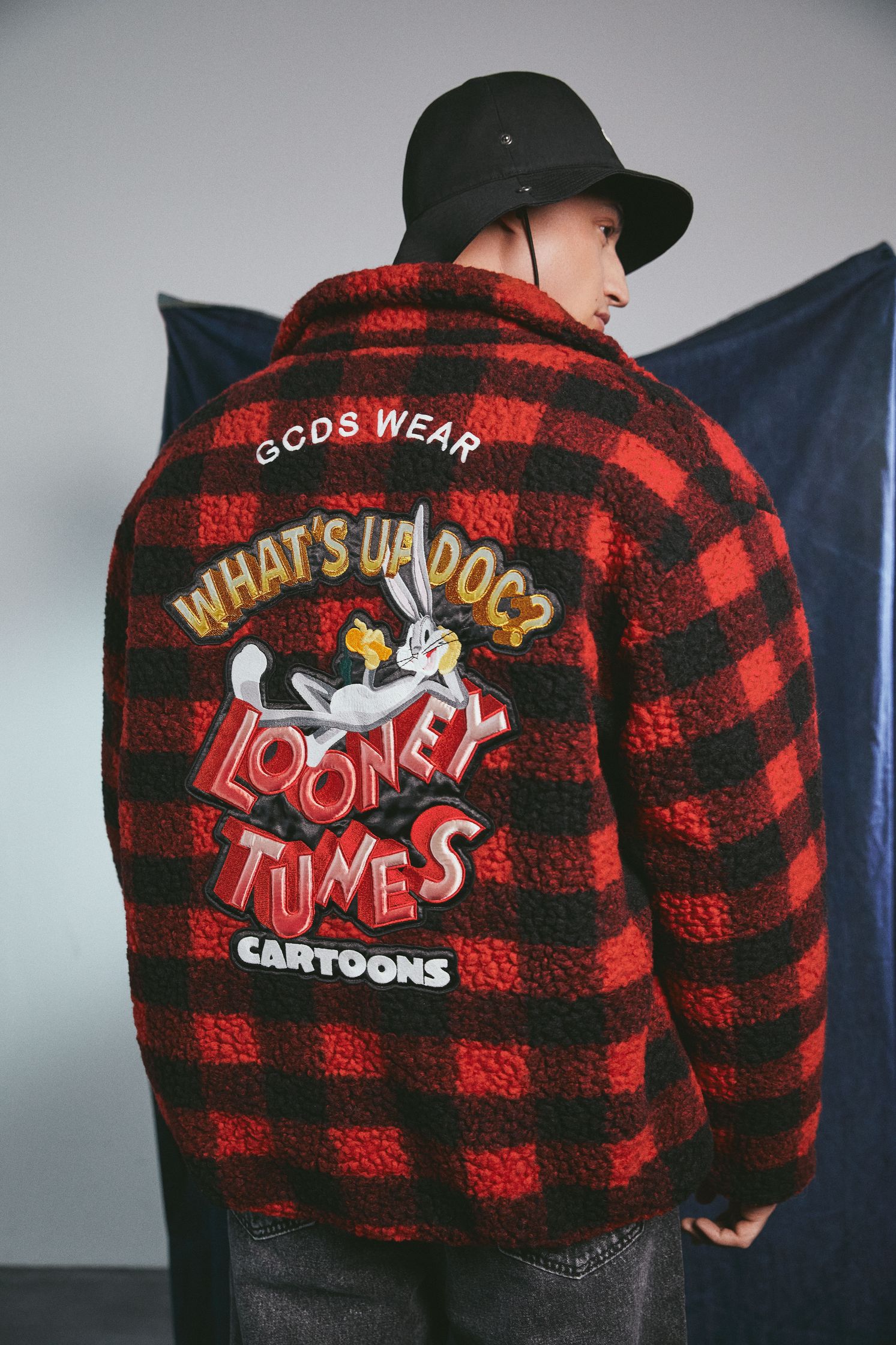 a man wearing a red and black plaid jacket with the words what's up times