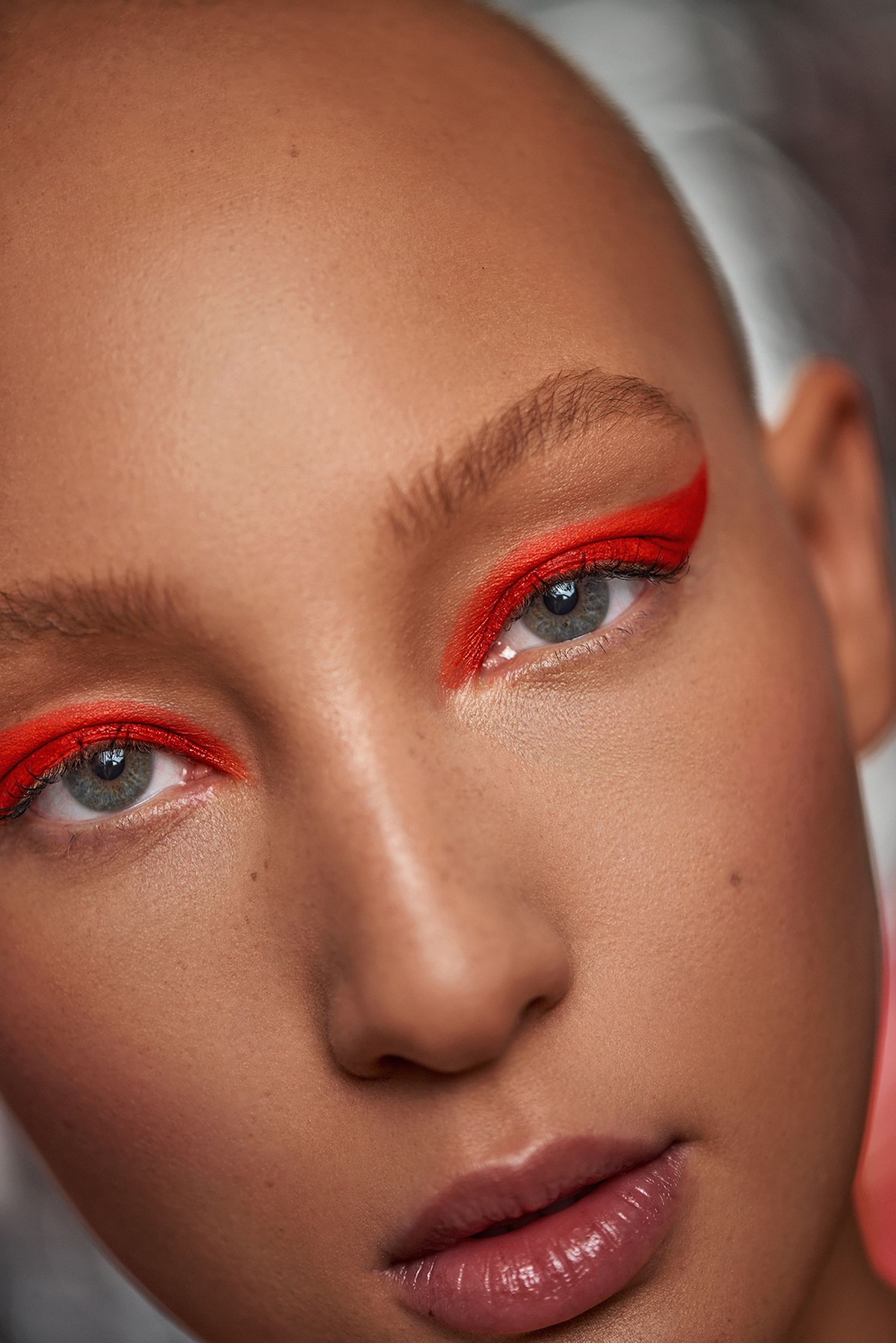a woman with red eye makeup and a bald head