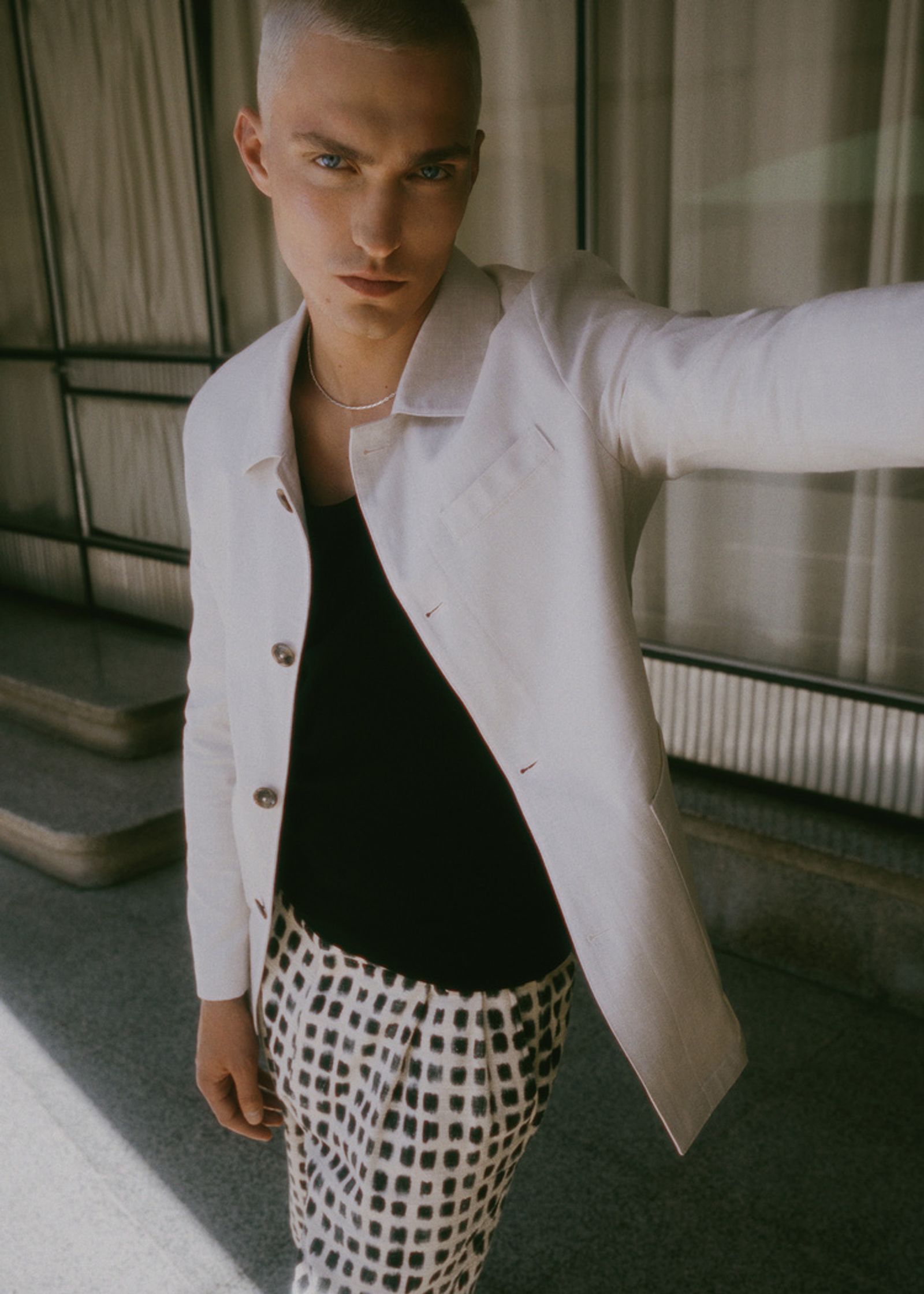 a young man in a white jacket and polka dot pants