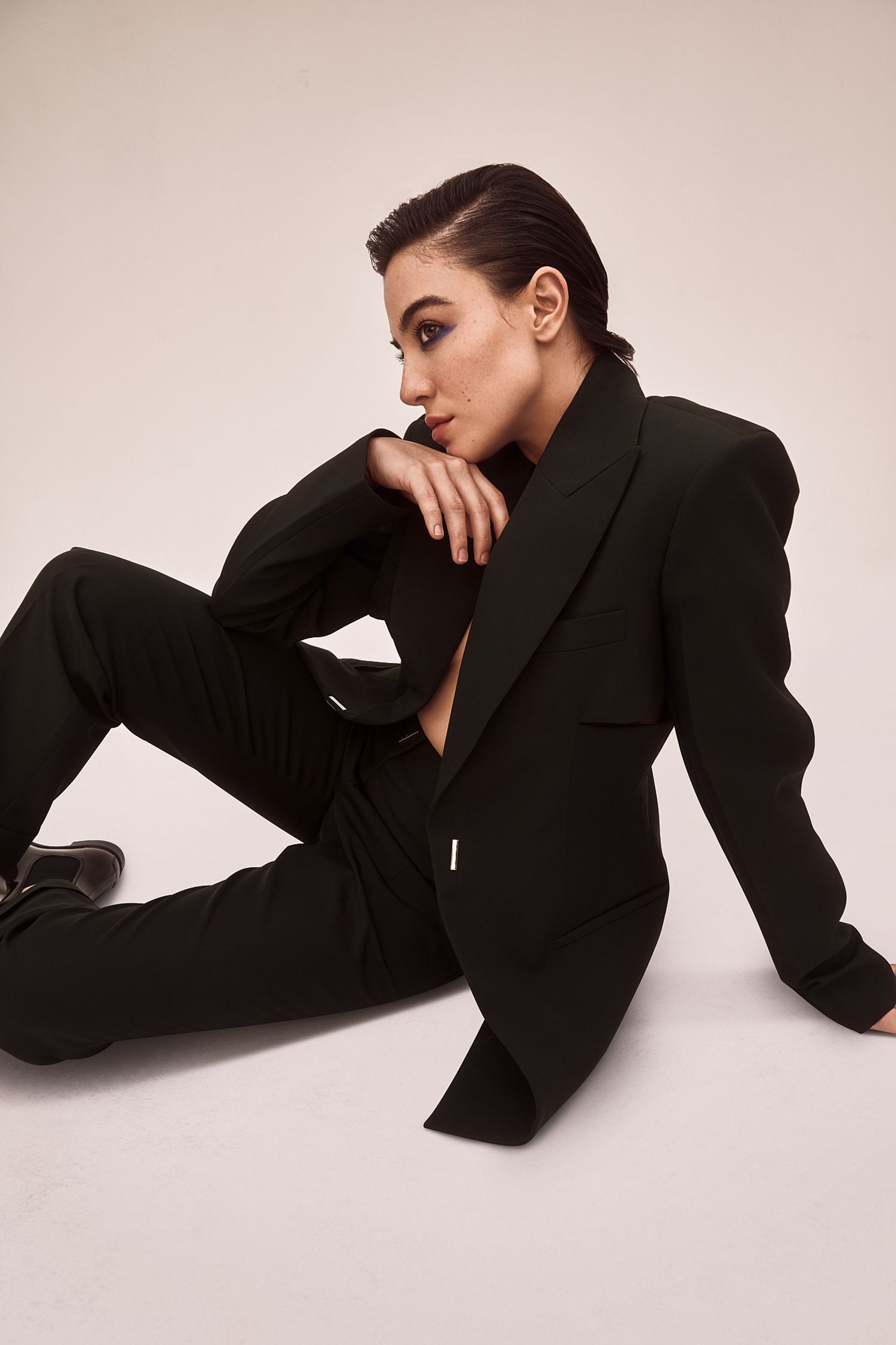 a woman in a black suit laying on the floor