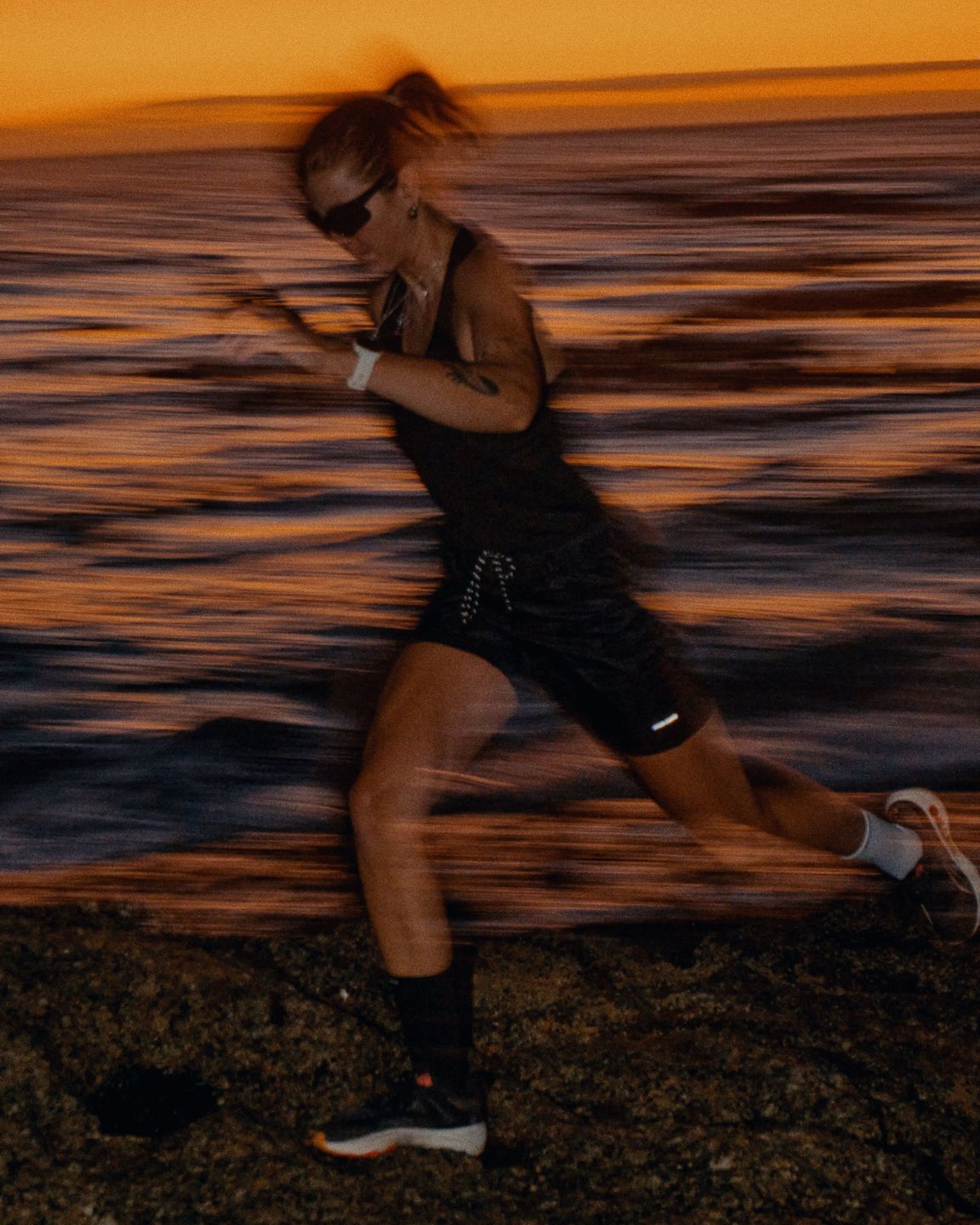 a woman running along the ocean at sunset by advertising photographer Martin Kula