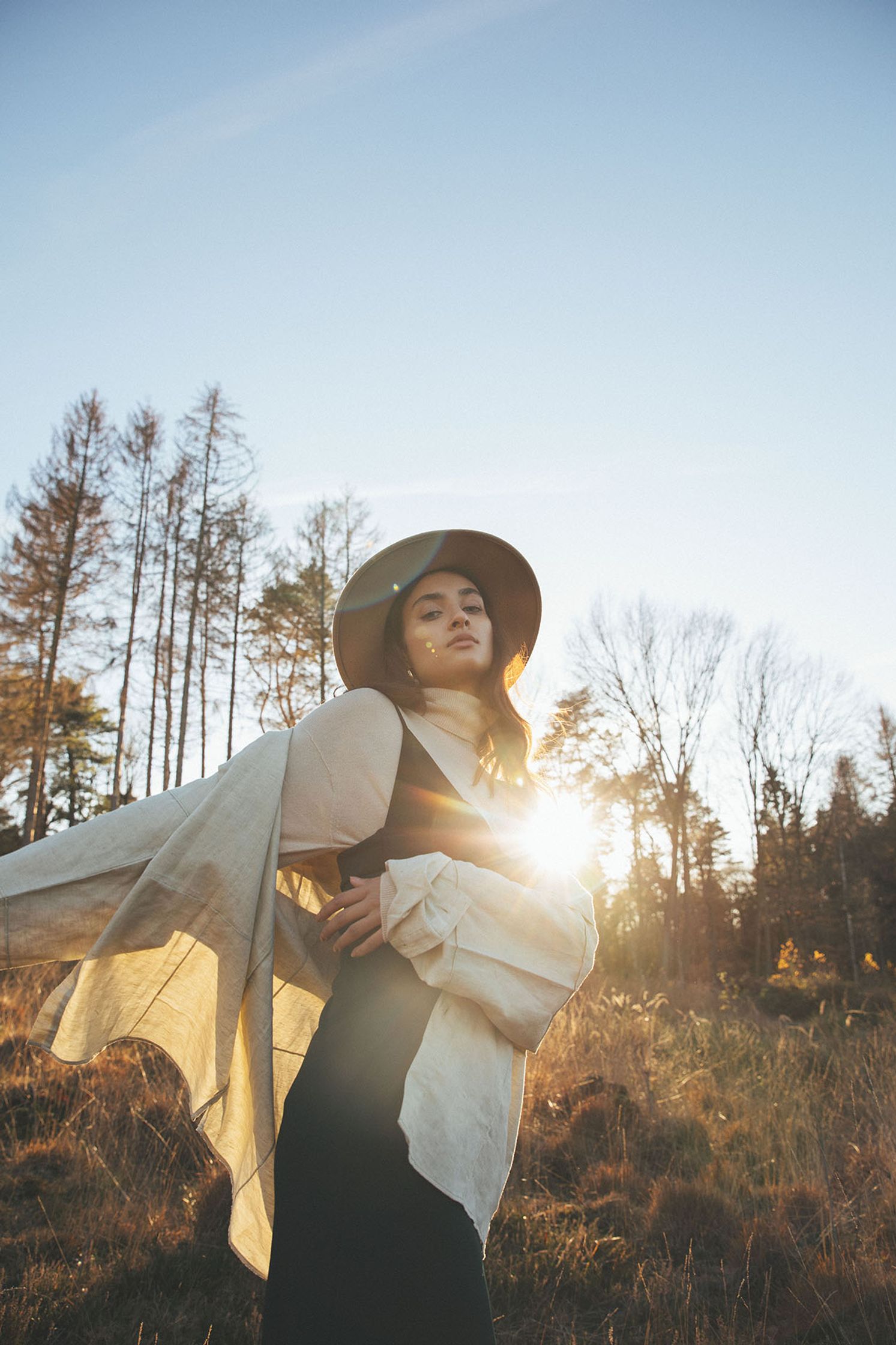 a woman in a hat is standing in a field