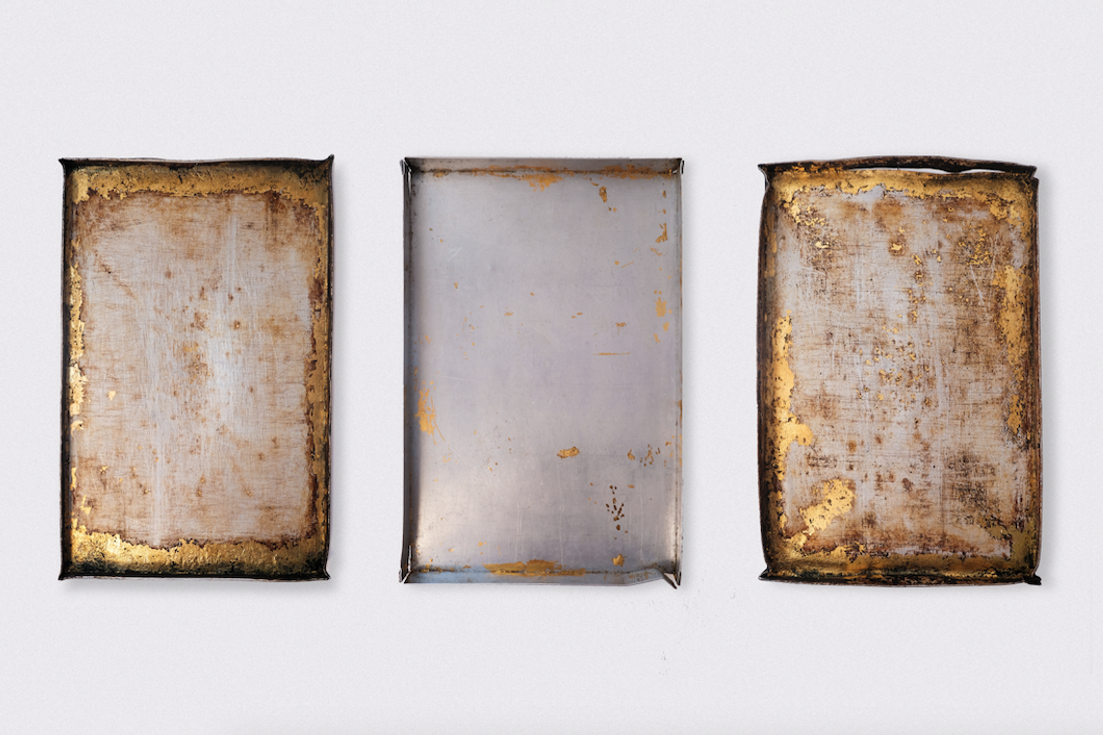Three rectangular panels, two with rust-colored edges and speckles of gold, flank a central light gray panel with subtle golden flecks, all against a white background.