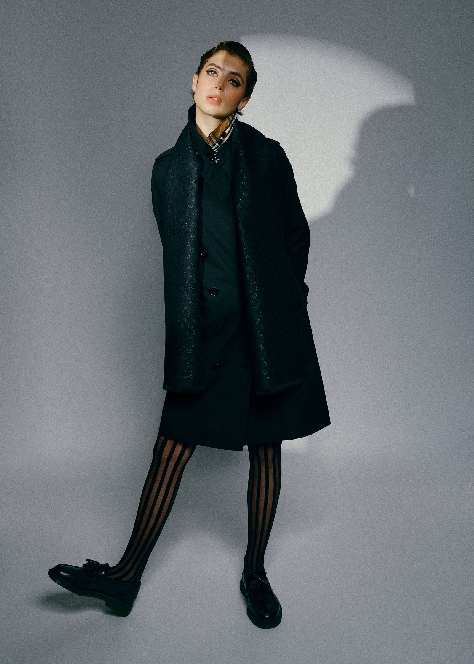a woman in a black coat and stockings posing for a photo